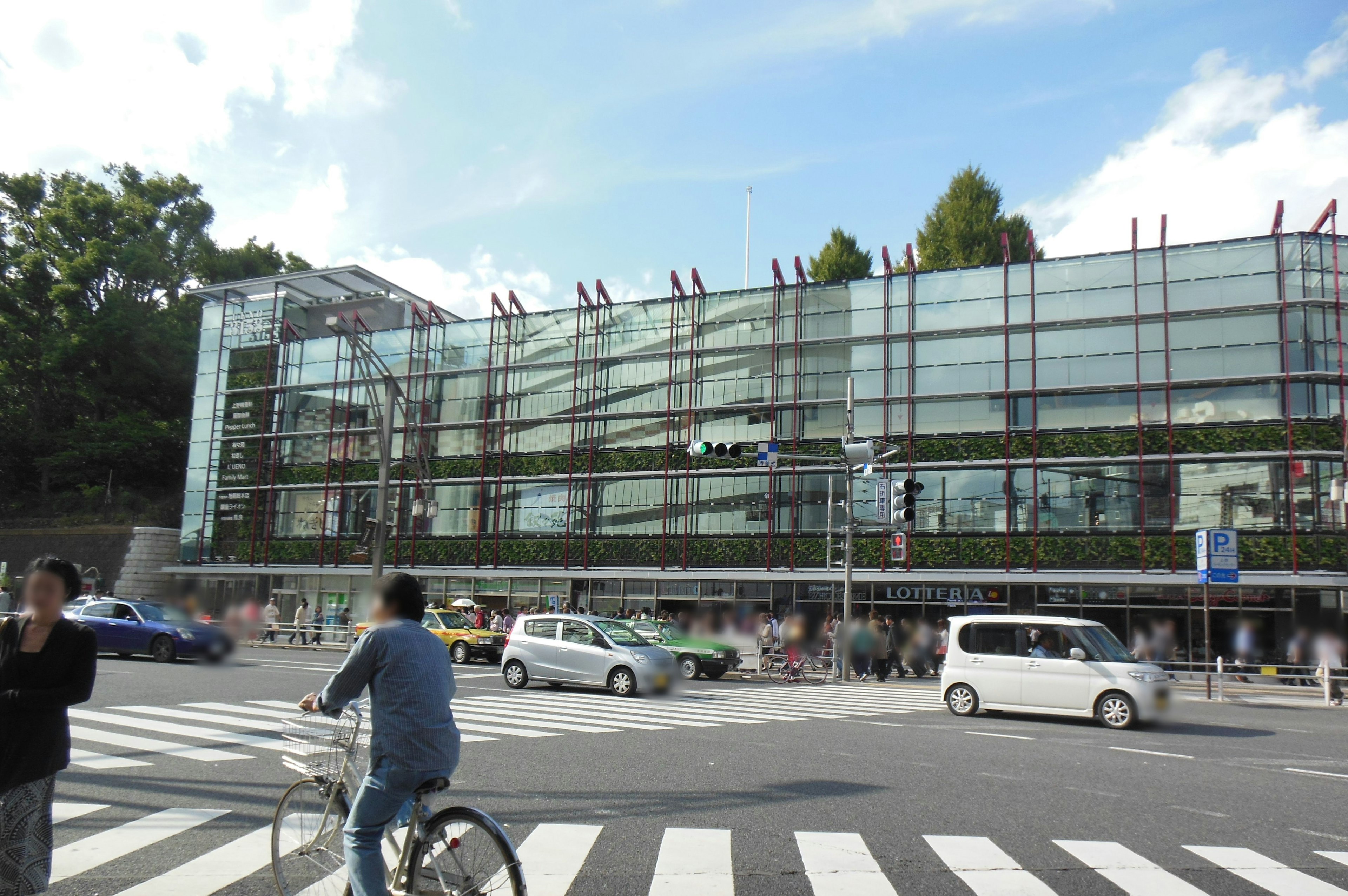 Bâtiment moderne en verre avec un cycliste traversant l'intersection