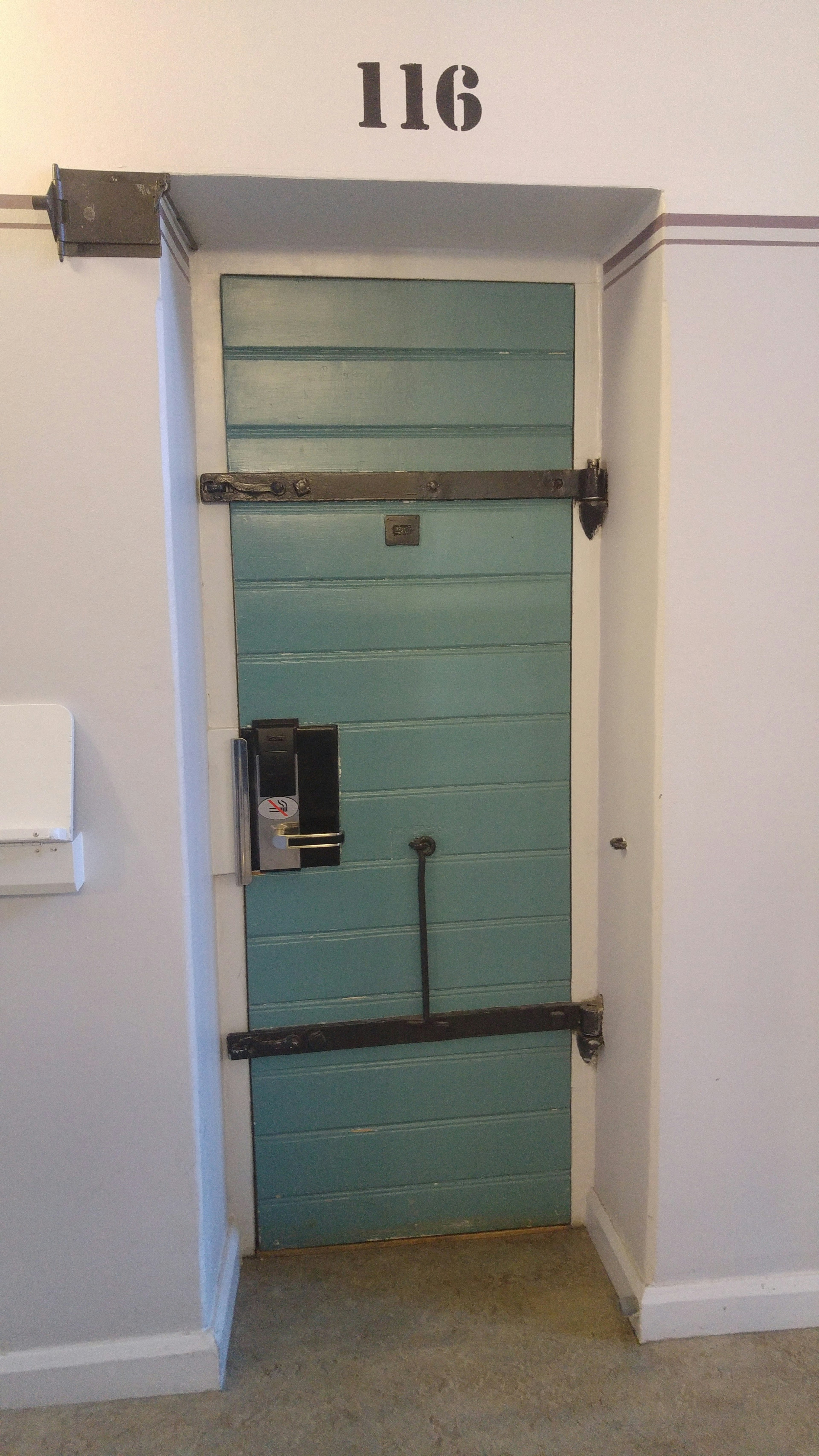 Pintu kamar 116 dengan warna biru dan pengunci metal