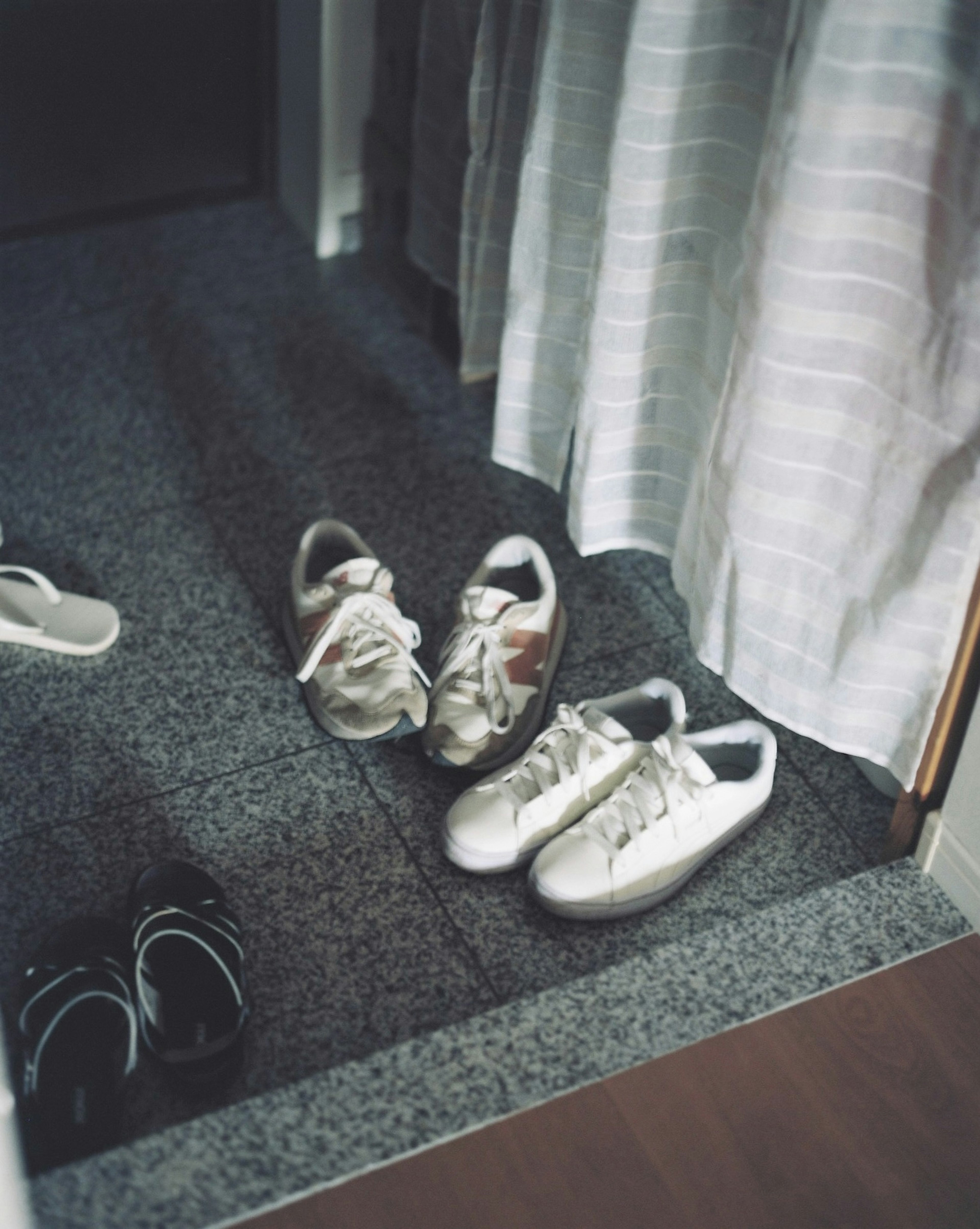 White sneakers and black sandals placed at the entrance