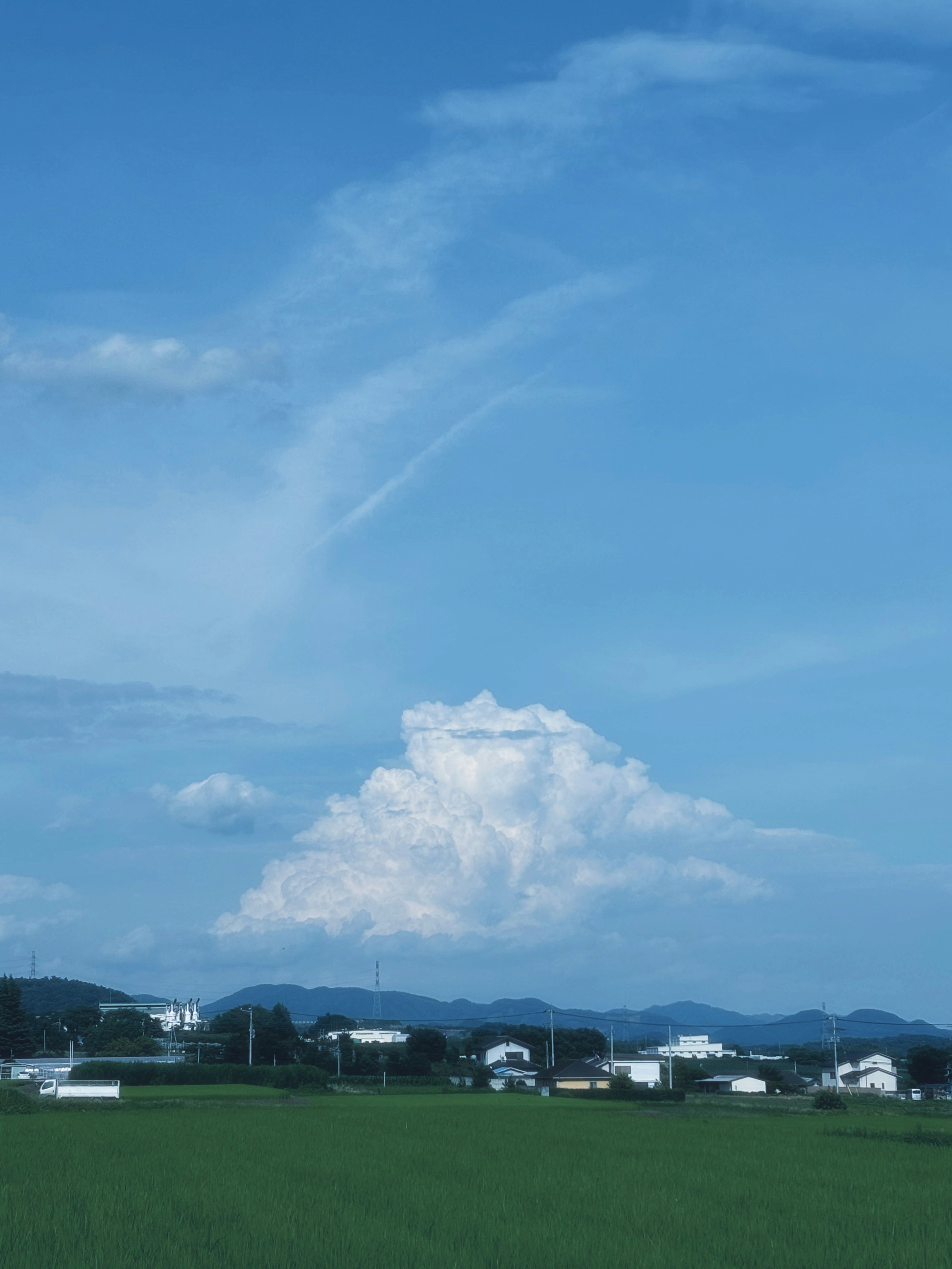 Nube grande en un cielo azul sobre un paisaje rural