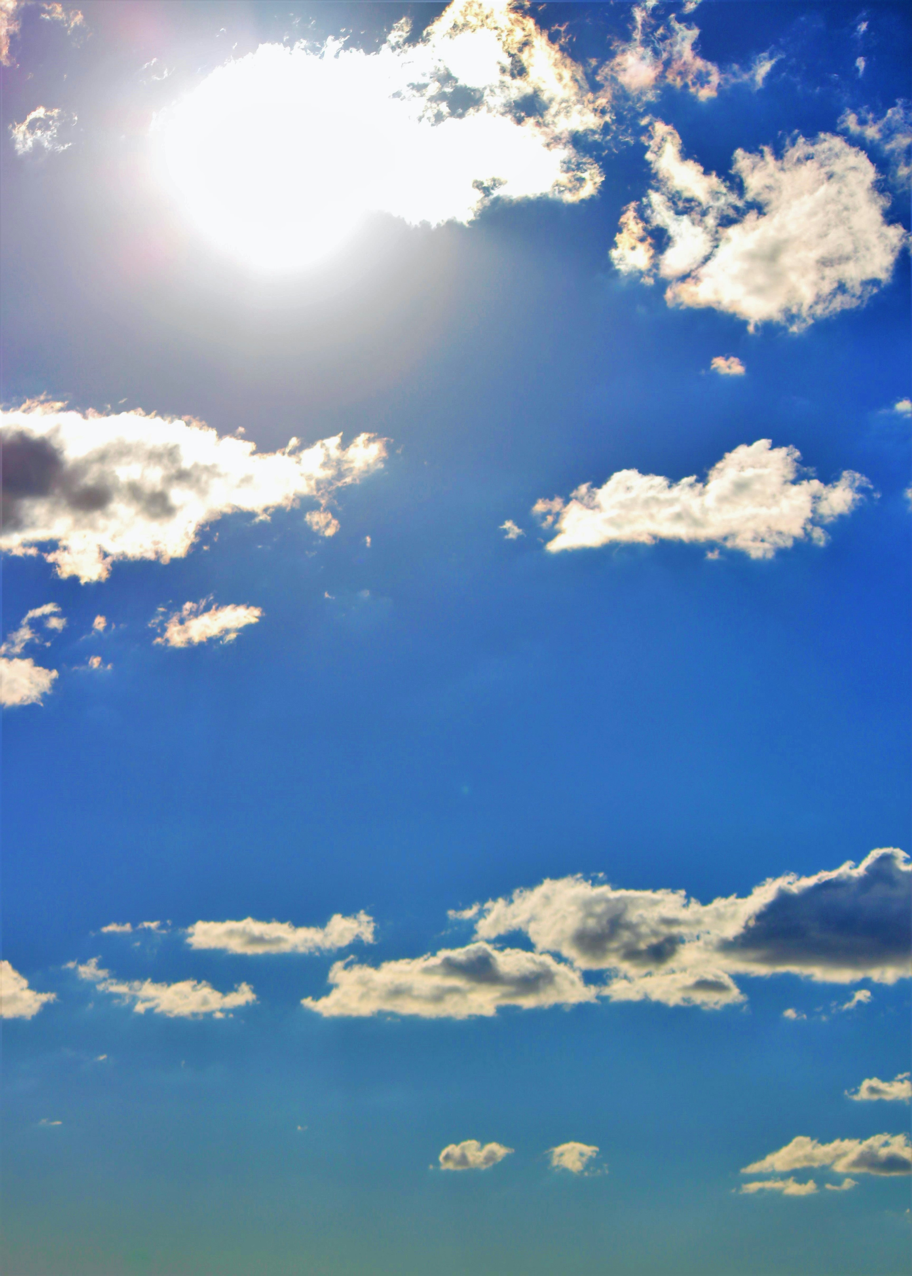 Bright blue sky with fluffy white clouds and the sun