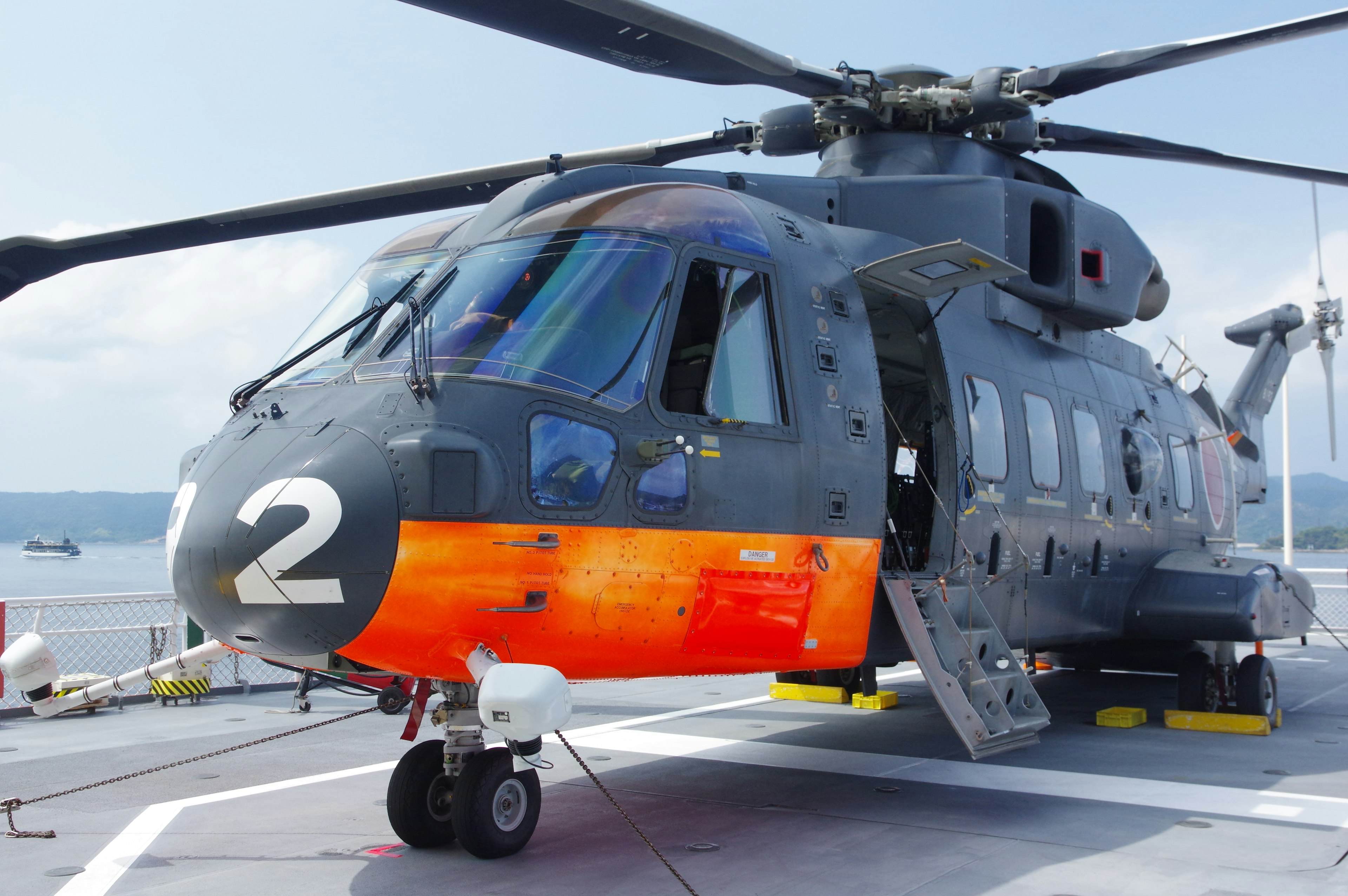 Helicóptero gris y naranja en un barco con el número 2 visible en su costado