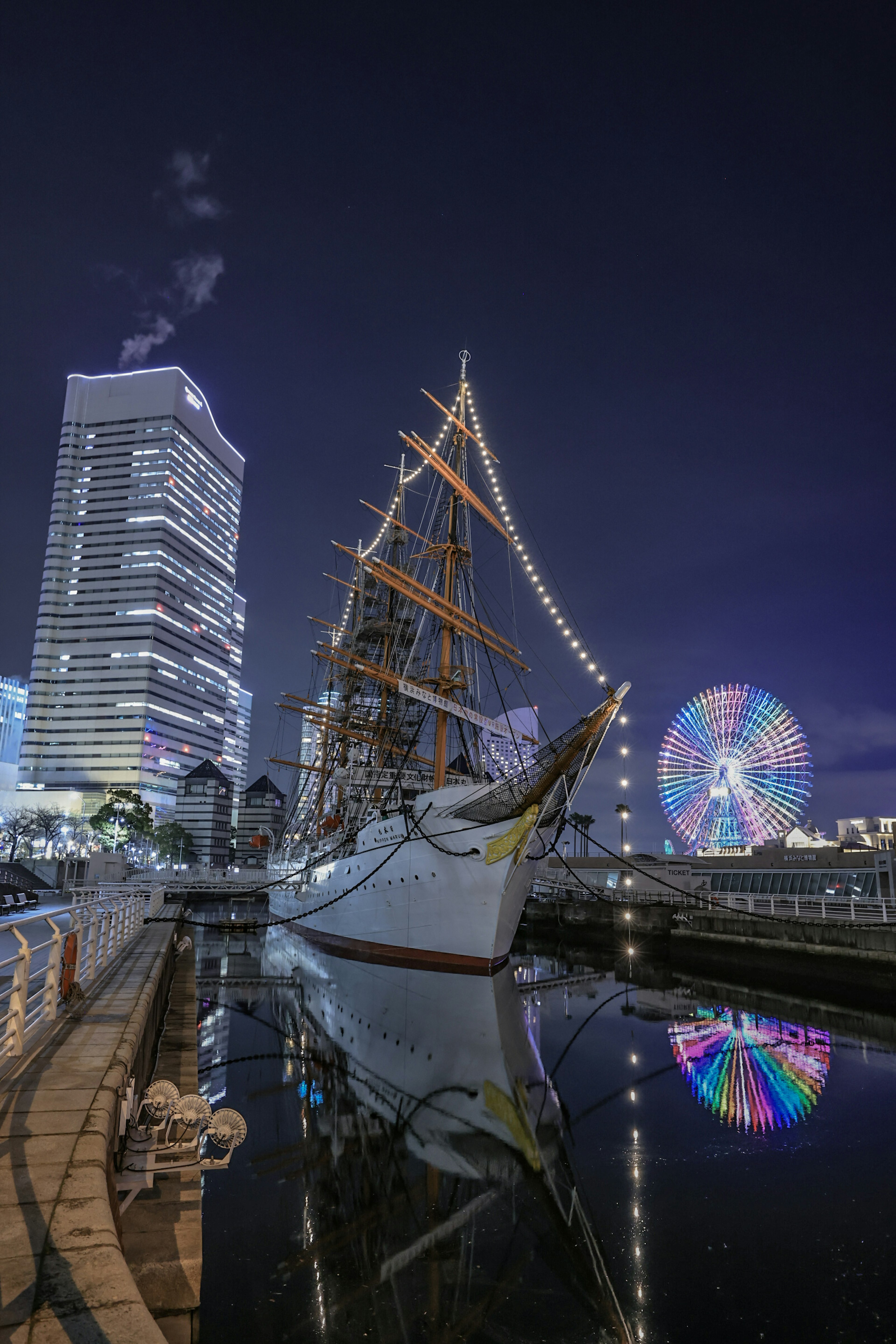 Barco de vela iluminado por la noche con una noria al fondo