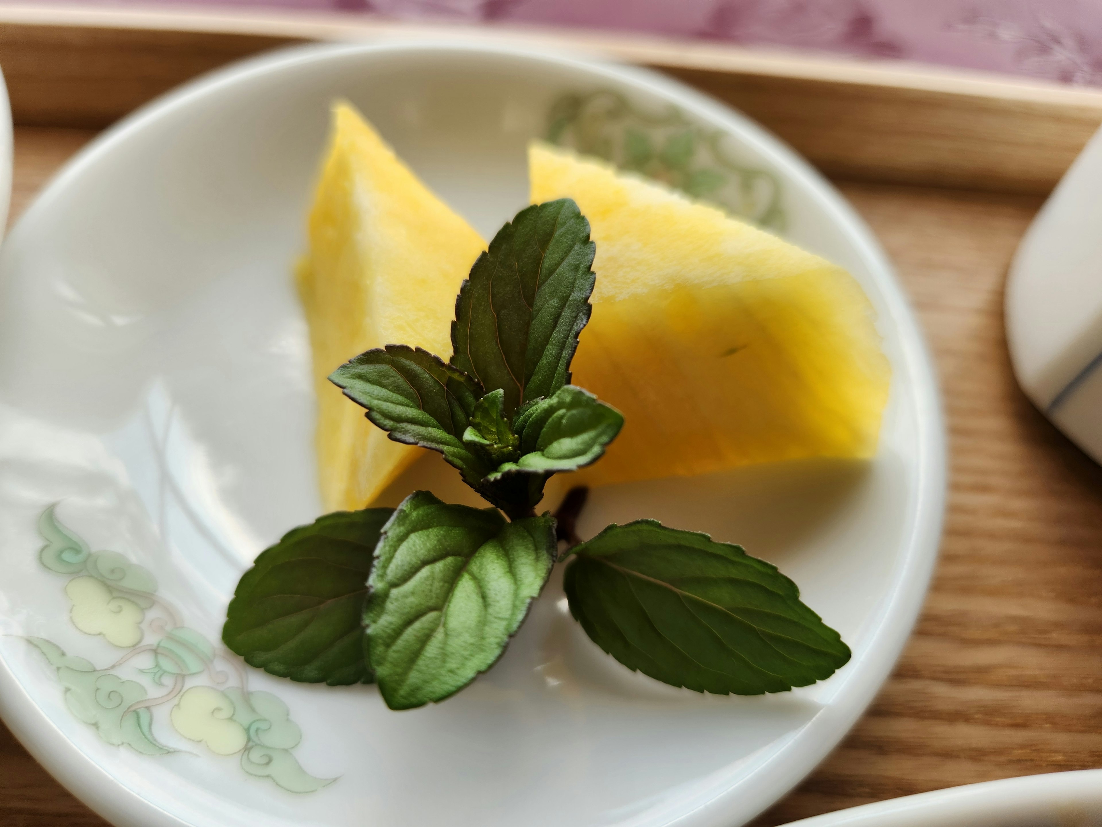 Sliced pineapple pieces with fresh mint leaves on a decorative plate