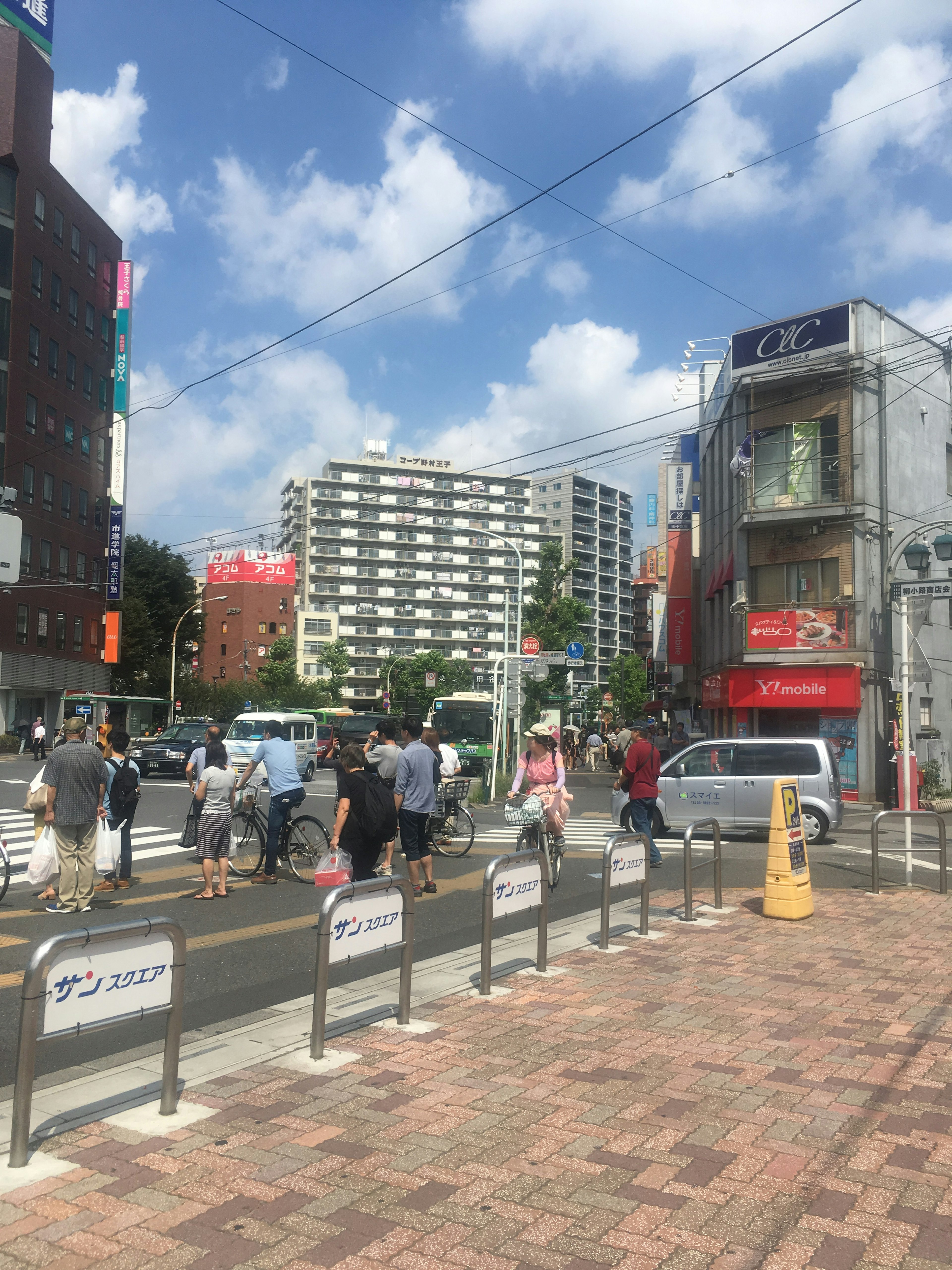 Busy street scene with people crossing the crosswalk buildings and blue sky