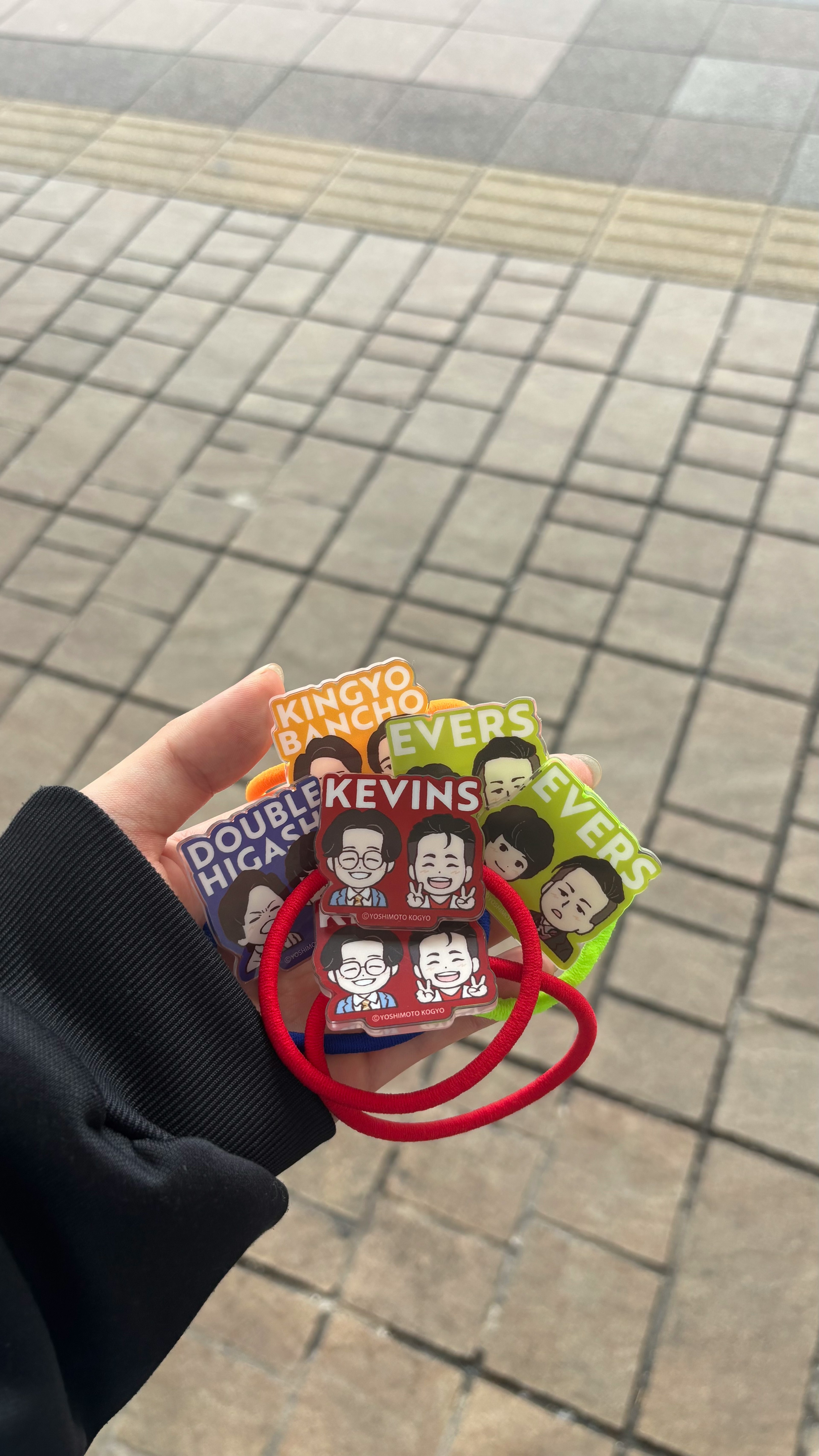 Colorful keychains held in hand with a red rubber band
