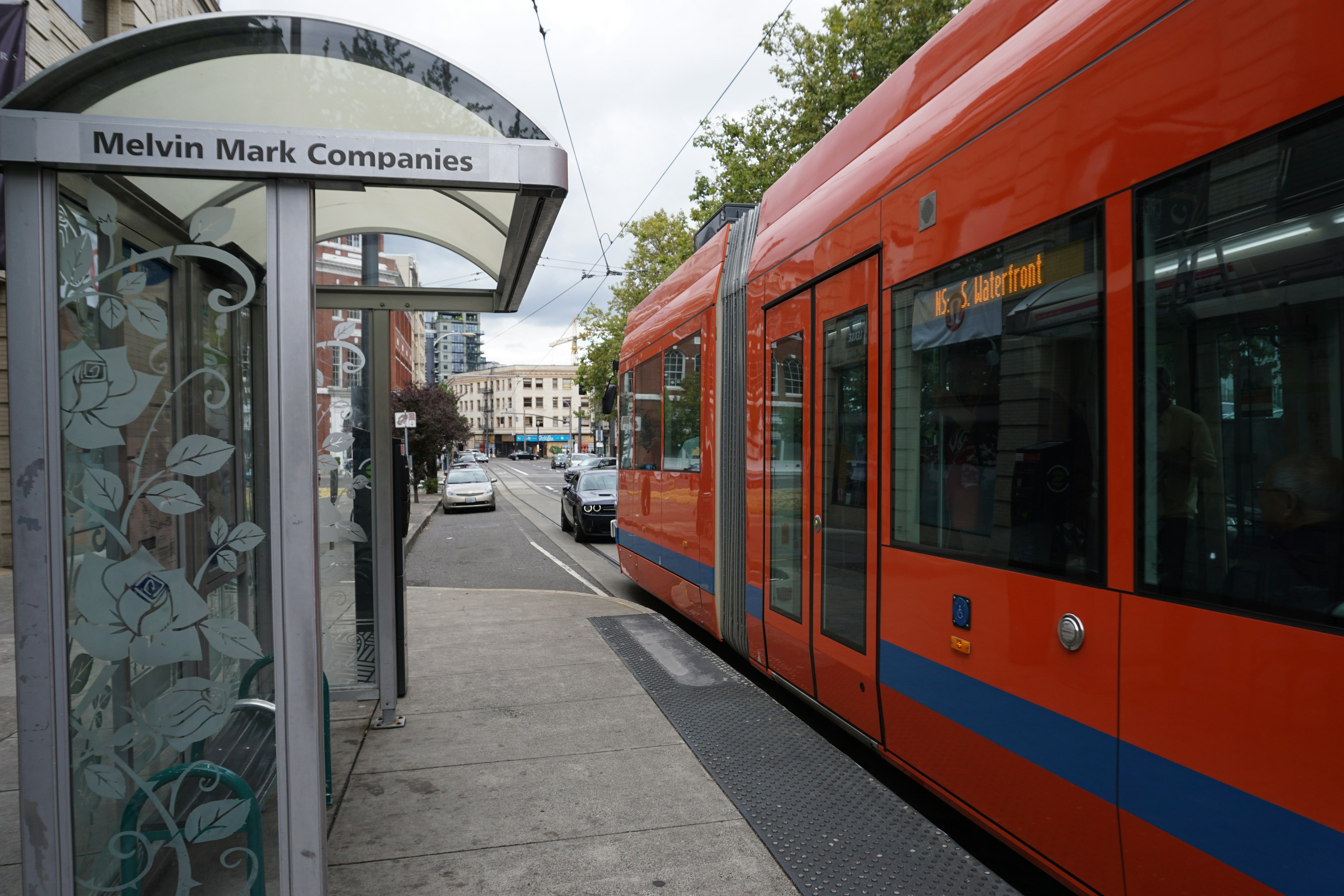 Arrêt de bus Melvin Mark Companies avec un tramway orange sur la rue