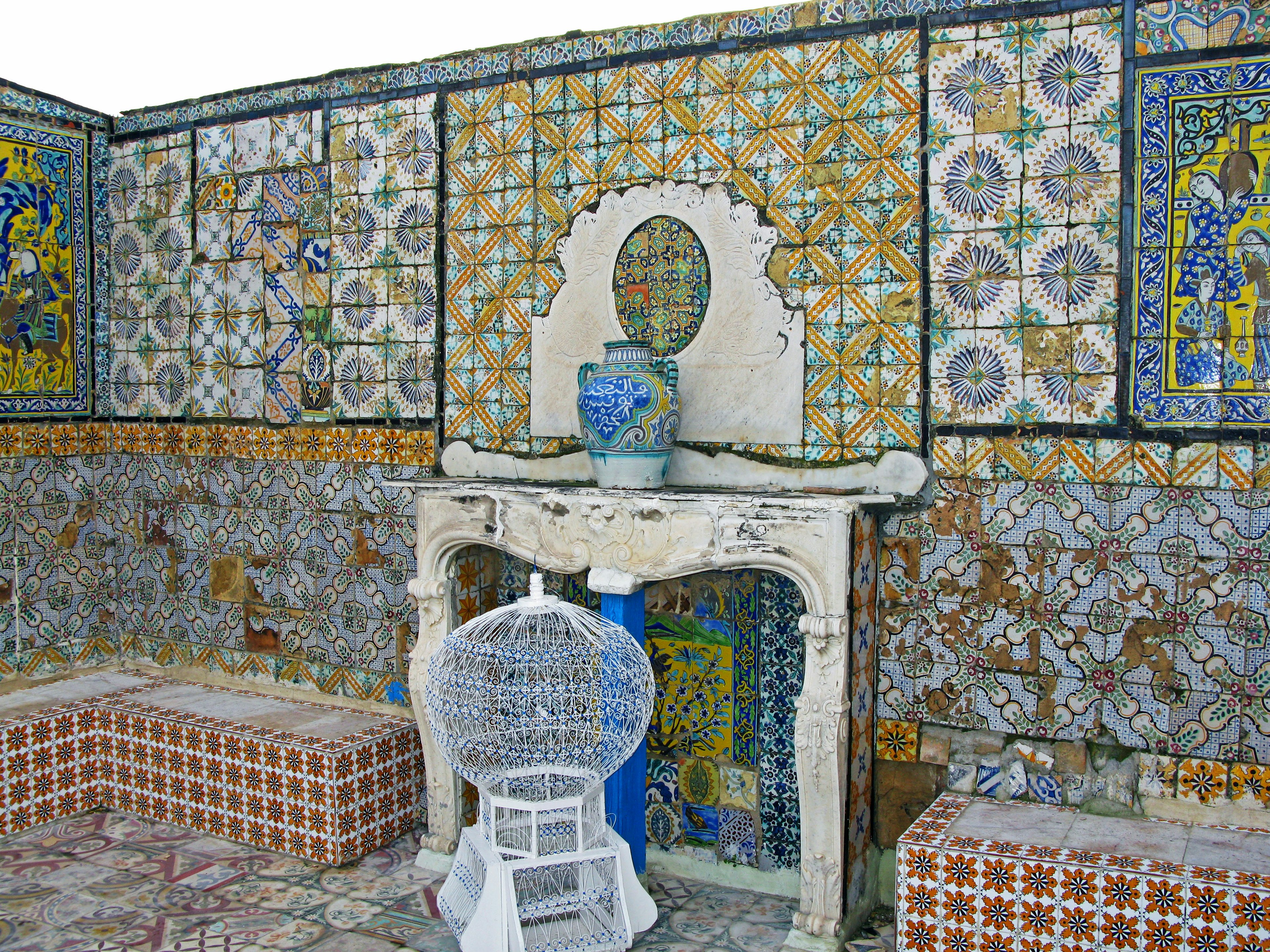 Interior de una habitación con paredes de azulejos decorativos y una silla blanca