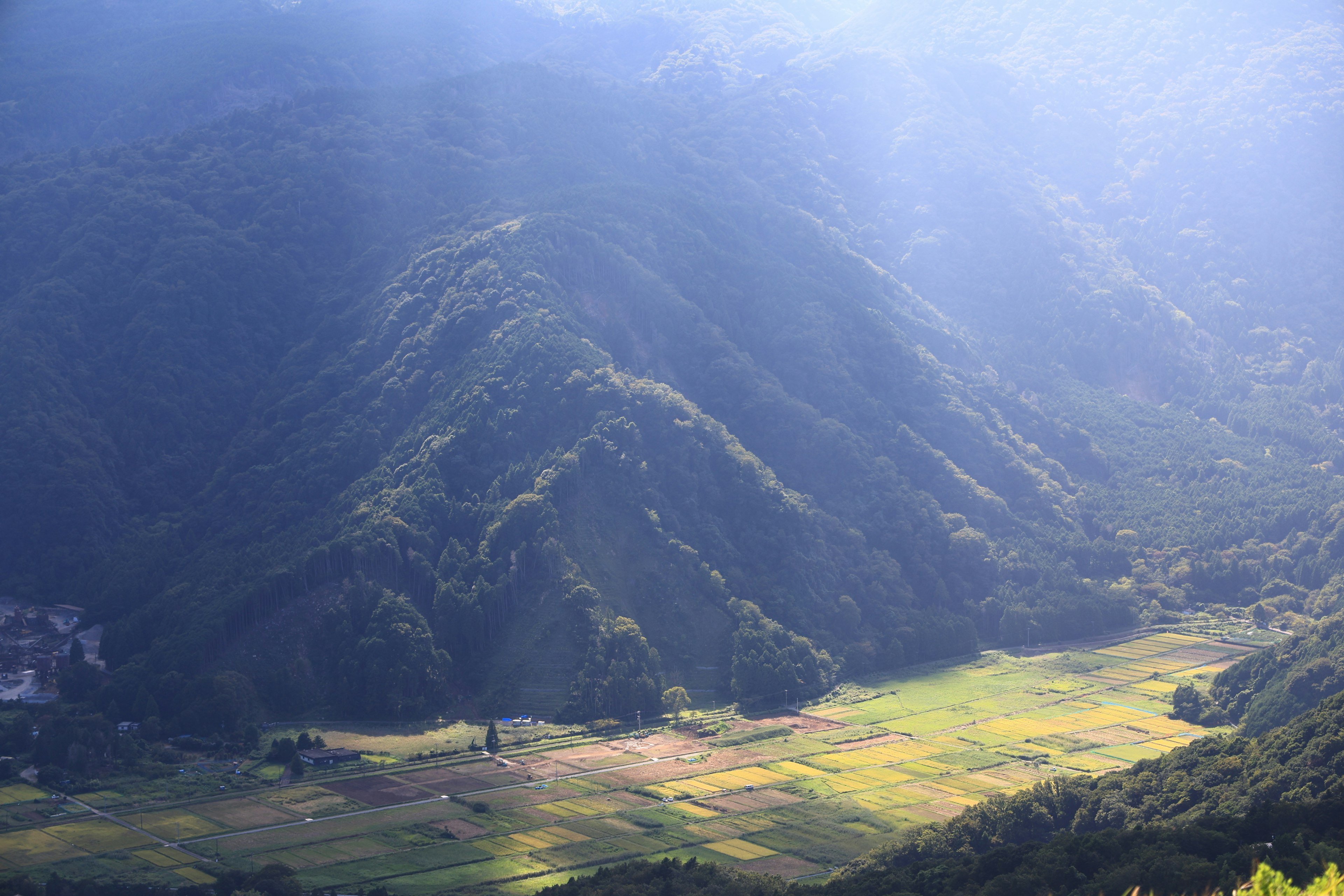 Malersiche Aussicht auf blaue Berge und grüne Felder im sanften Sonnenlicht