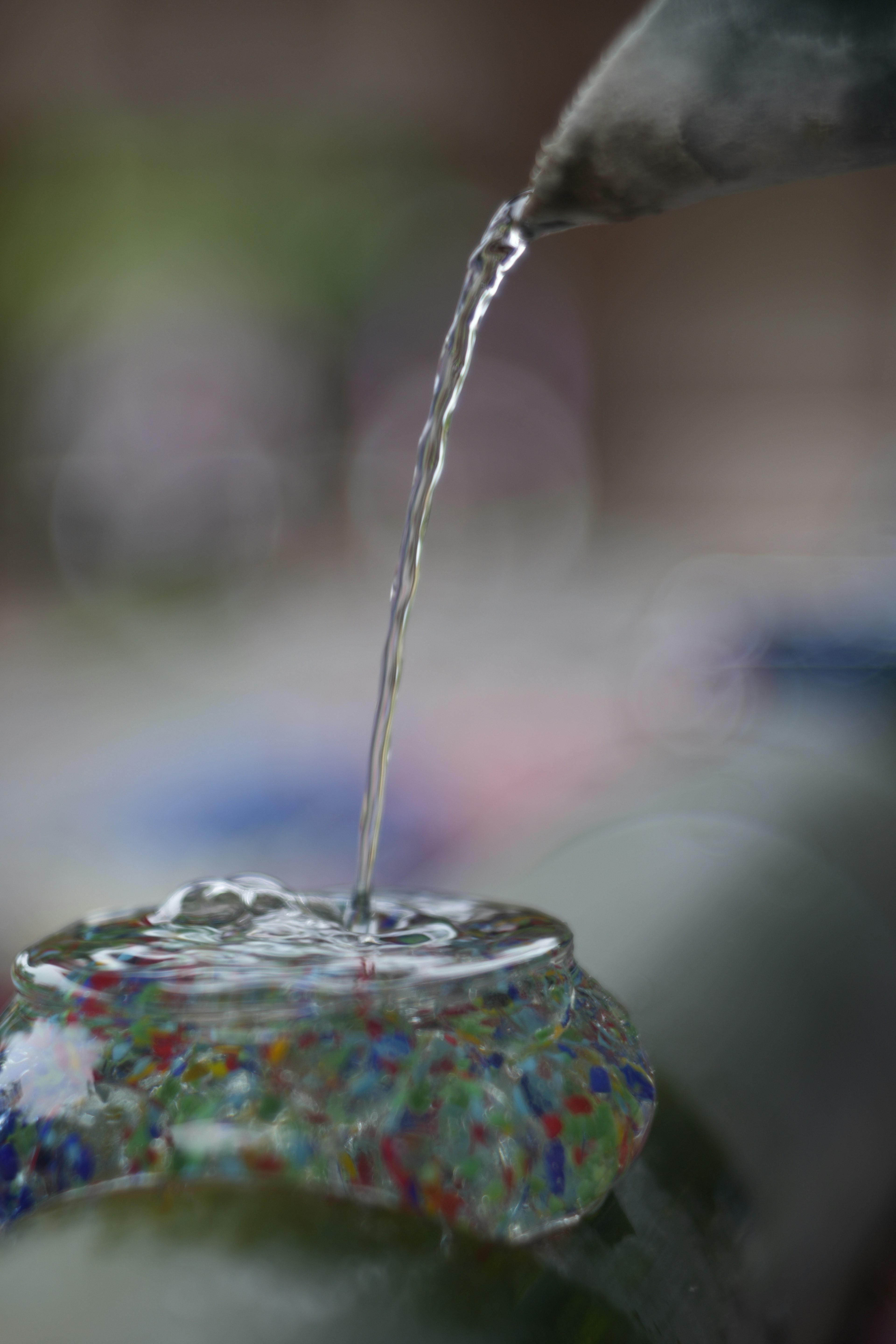 Bild zeigt Wasser, das aus einem Auslauf auf eine bunte Oberfläche mit Wellen fließt