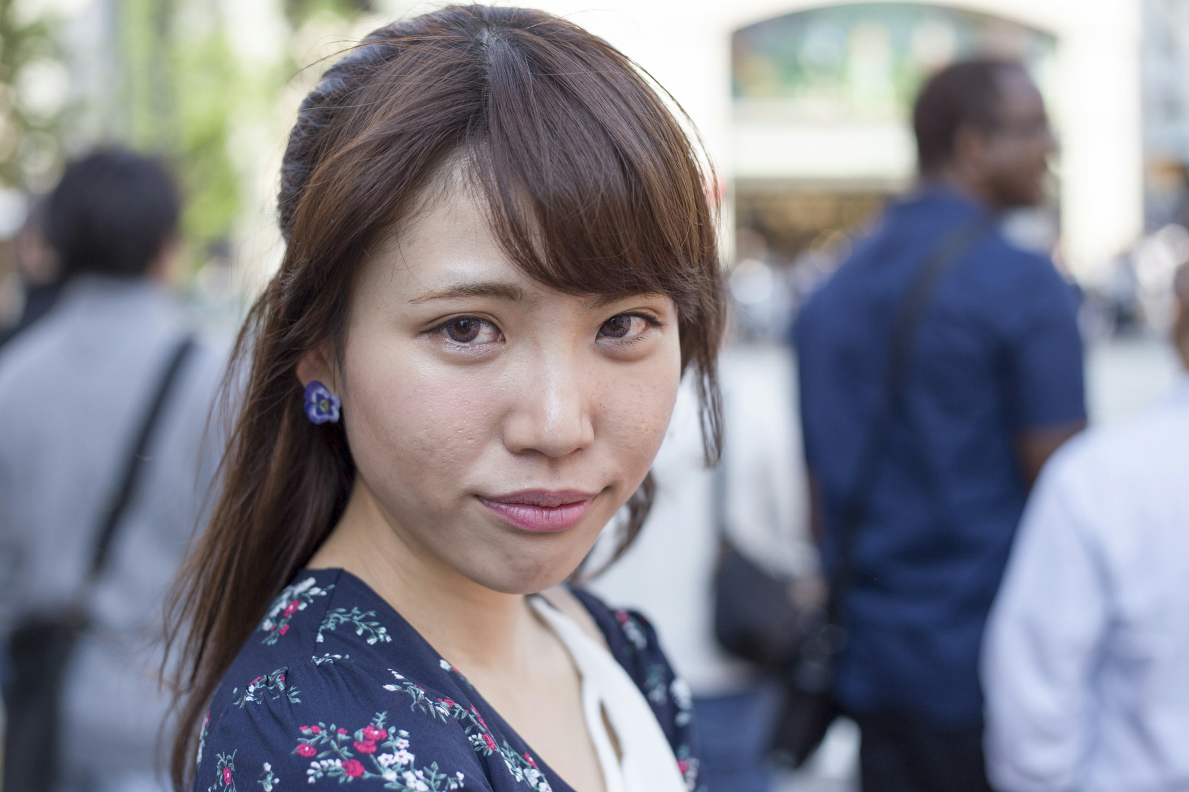 Portrait of a woman wearing floral clothing with people in the background