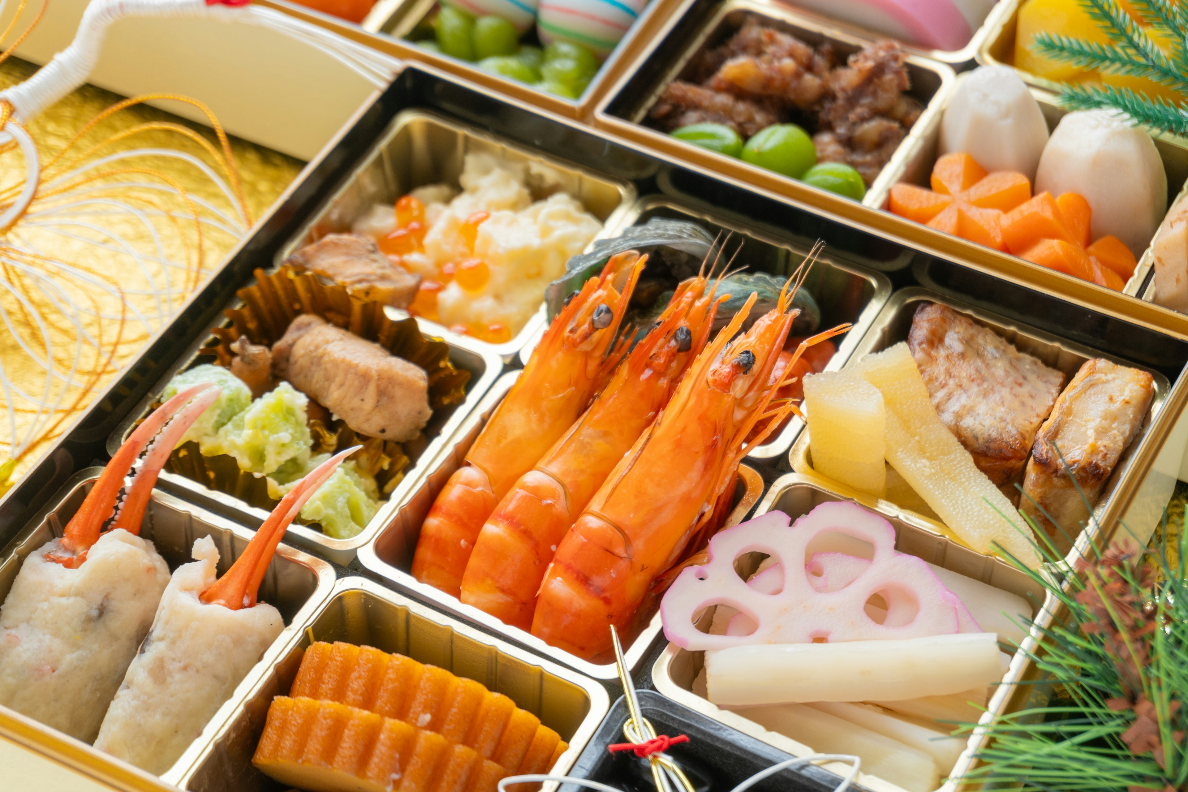 A colorful arrangement of sushi, shrimp, and vegetables in a traditional Japanese osechi dish