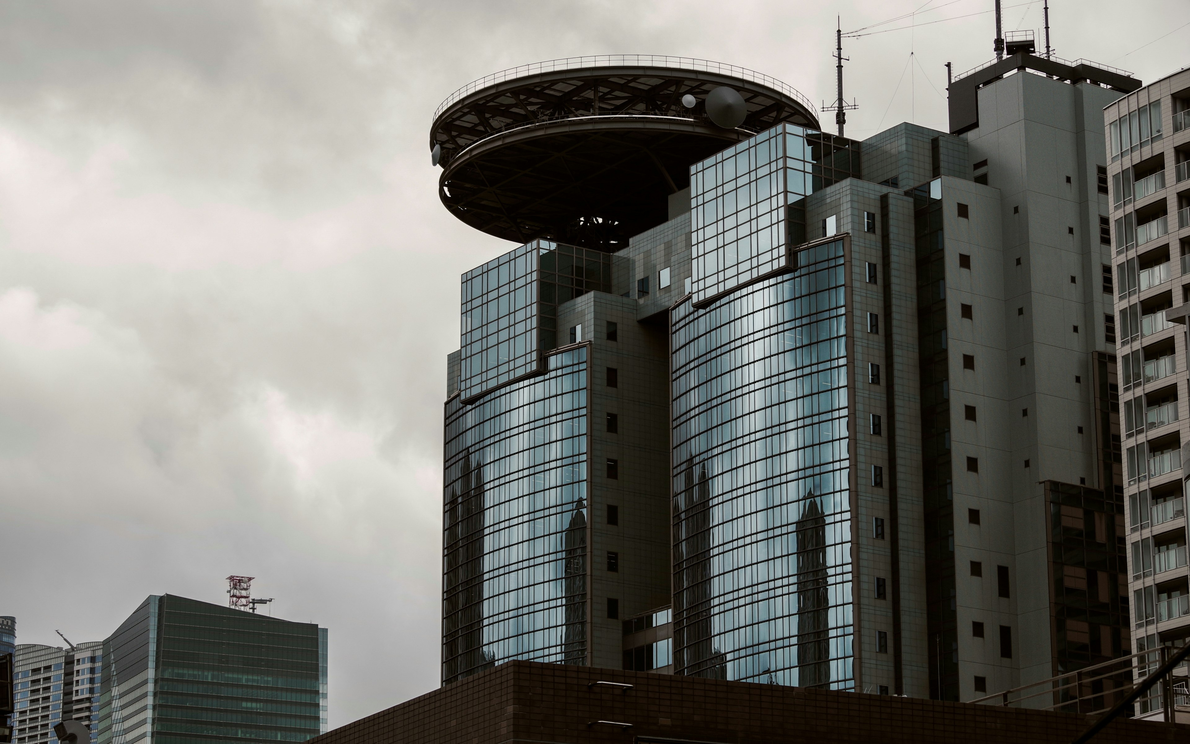 Bâtiment futuriste avec une structure circulaire sur le dessus contre un ciel nuageux