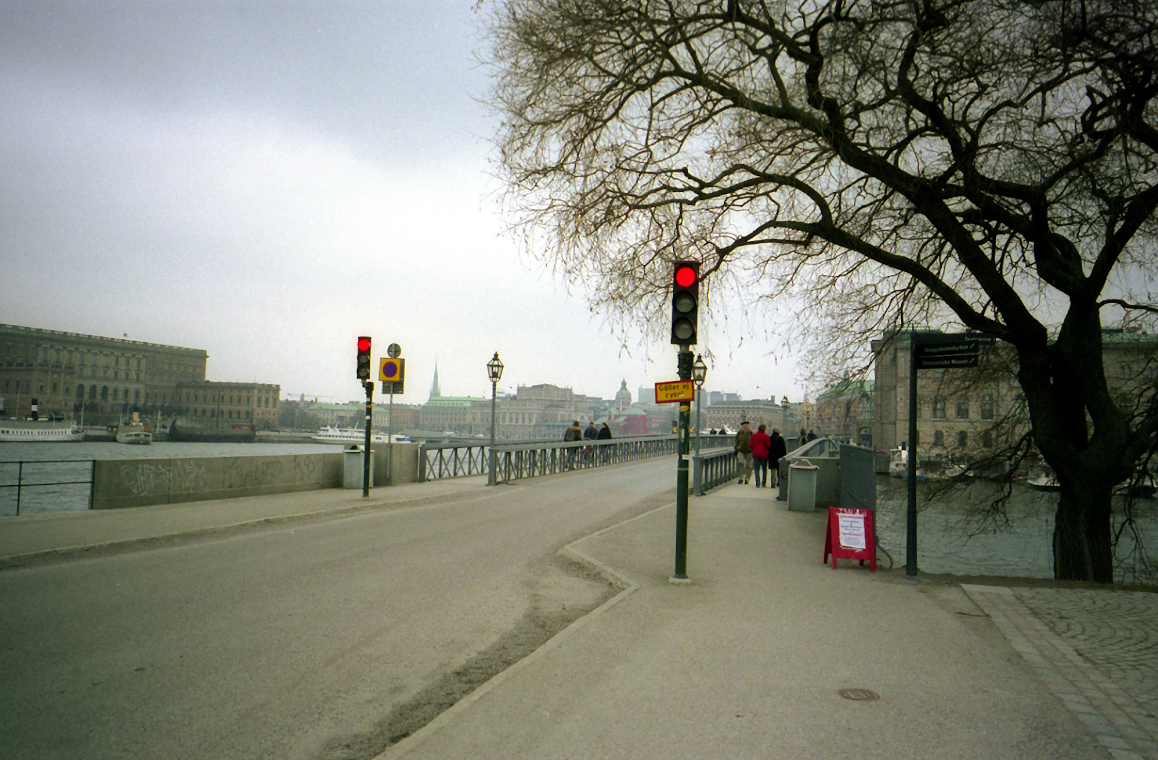 Quiet street scene with traffic lights and a bridge under a cloudy sky