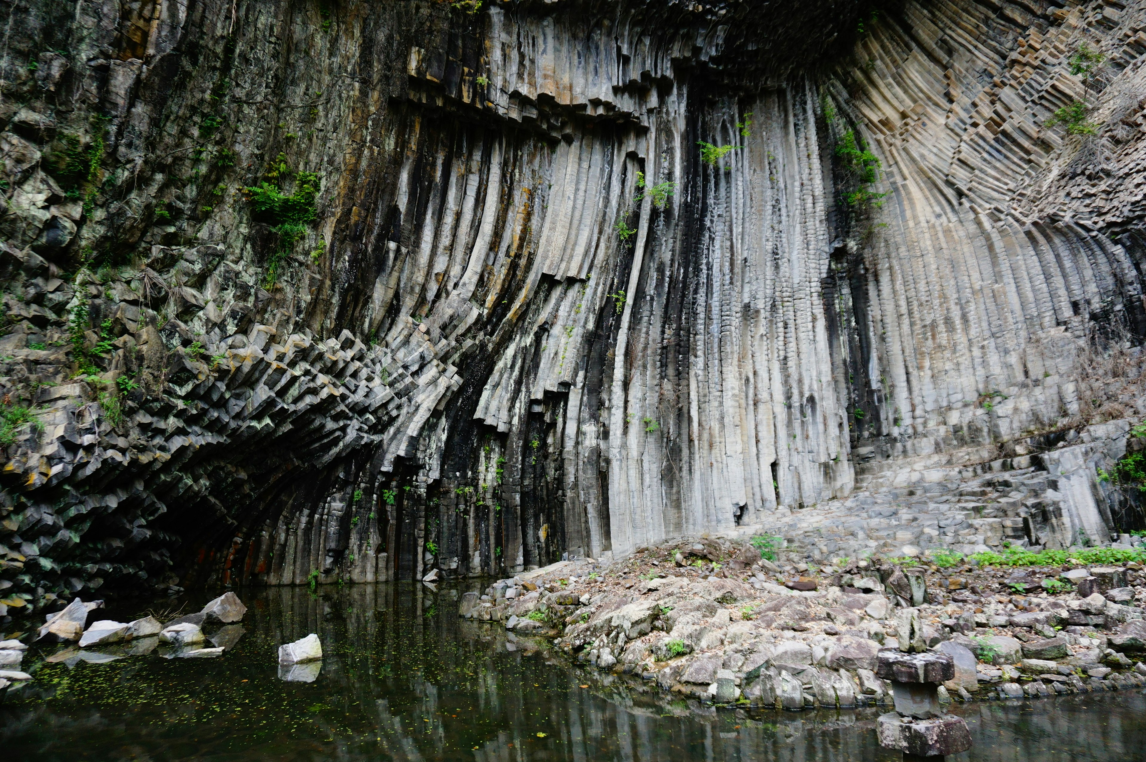 Beeindruckende säulenförmige Felsformation, die sich im ruhigen Wasser spiegelt