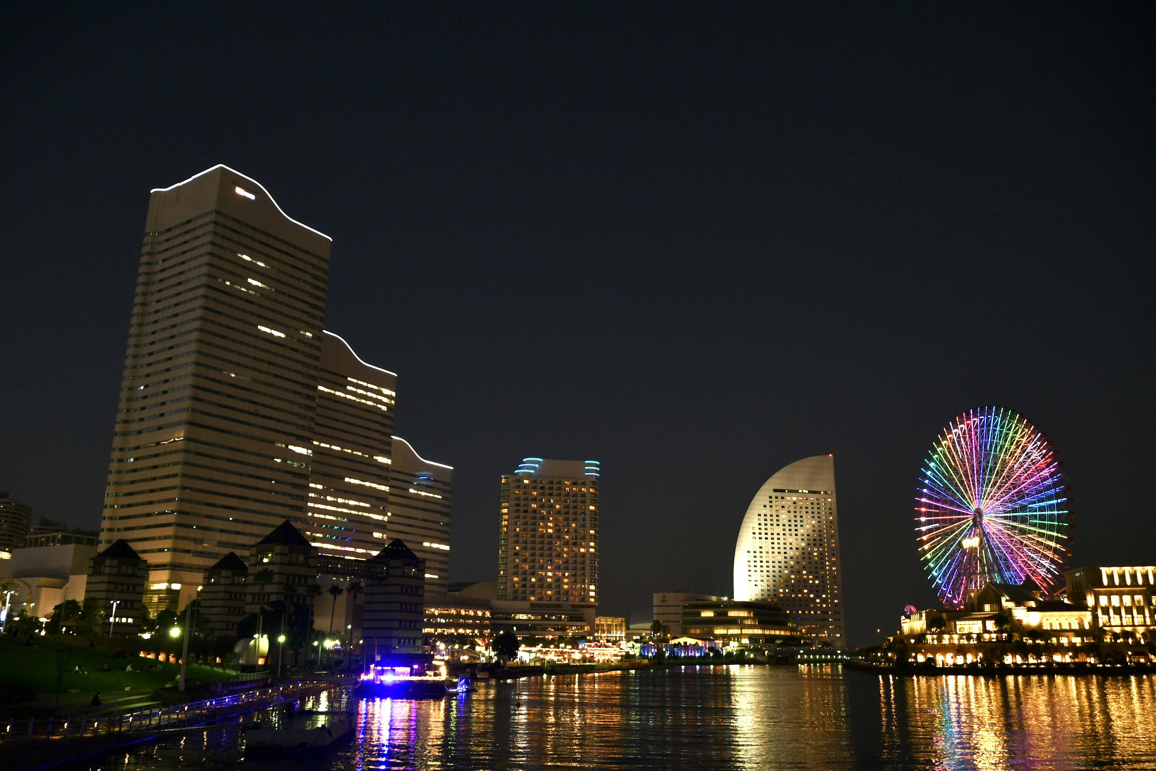 Vista notturna di Yokohama con grattacieli e ruota panoramica riflessi nell'acqua