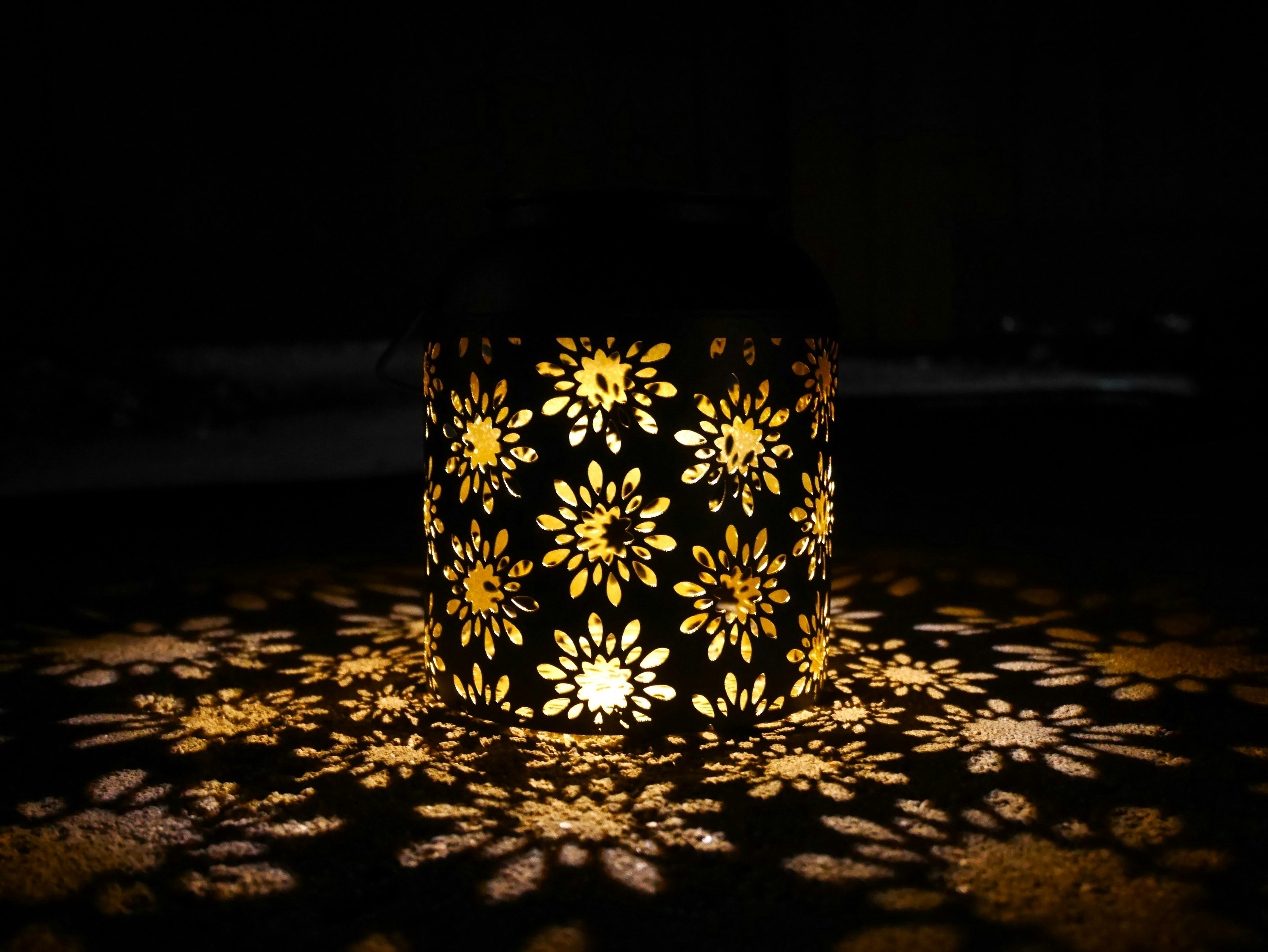 A decorative lantern with floral patterns casting warm light and intricate shadows