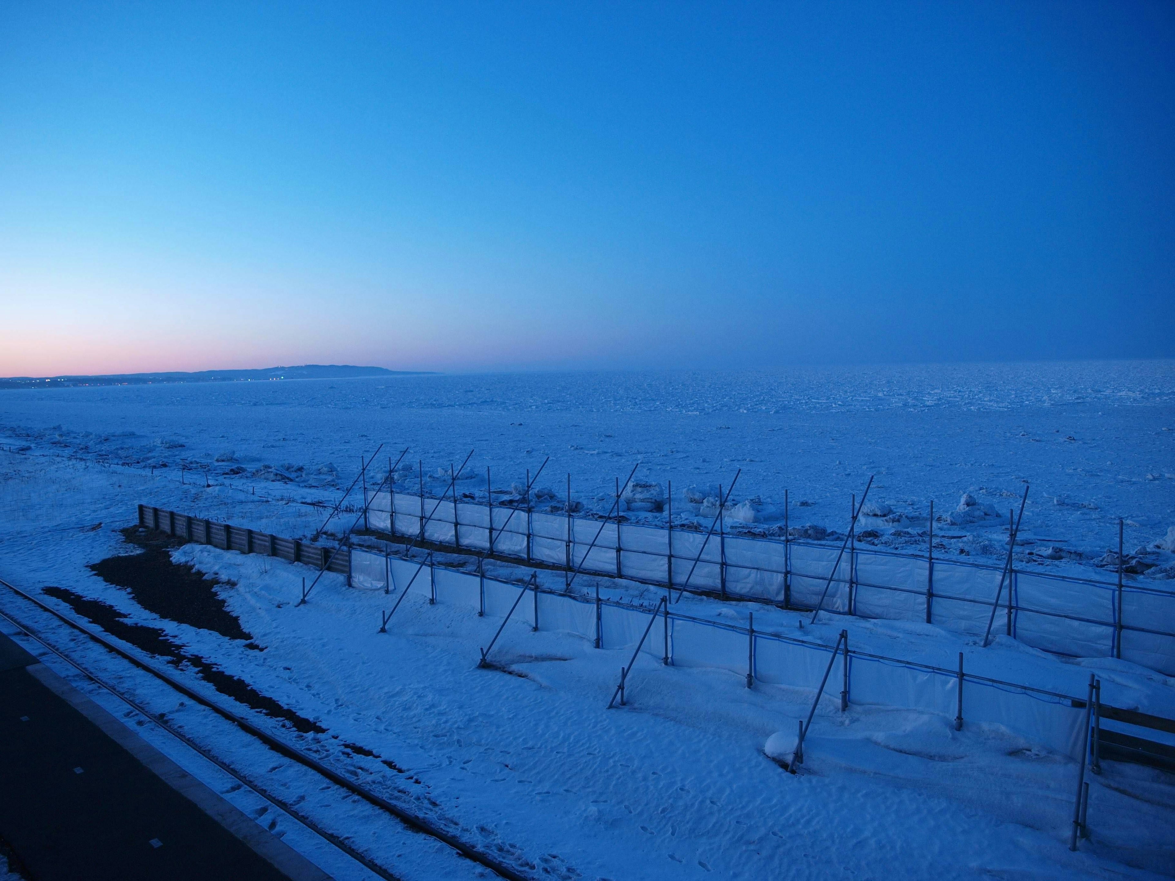 Vast snowy landscape under a blue sky at dusk