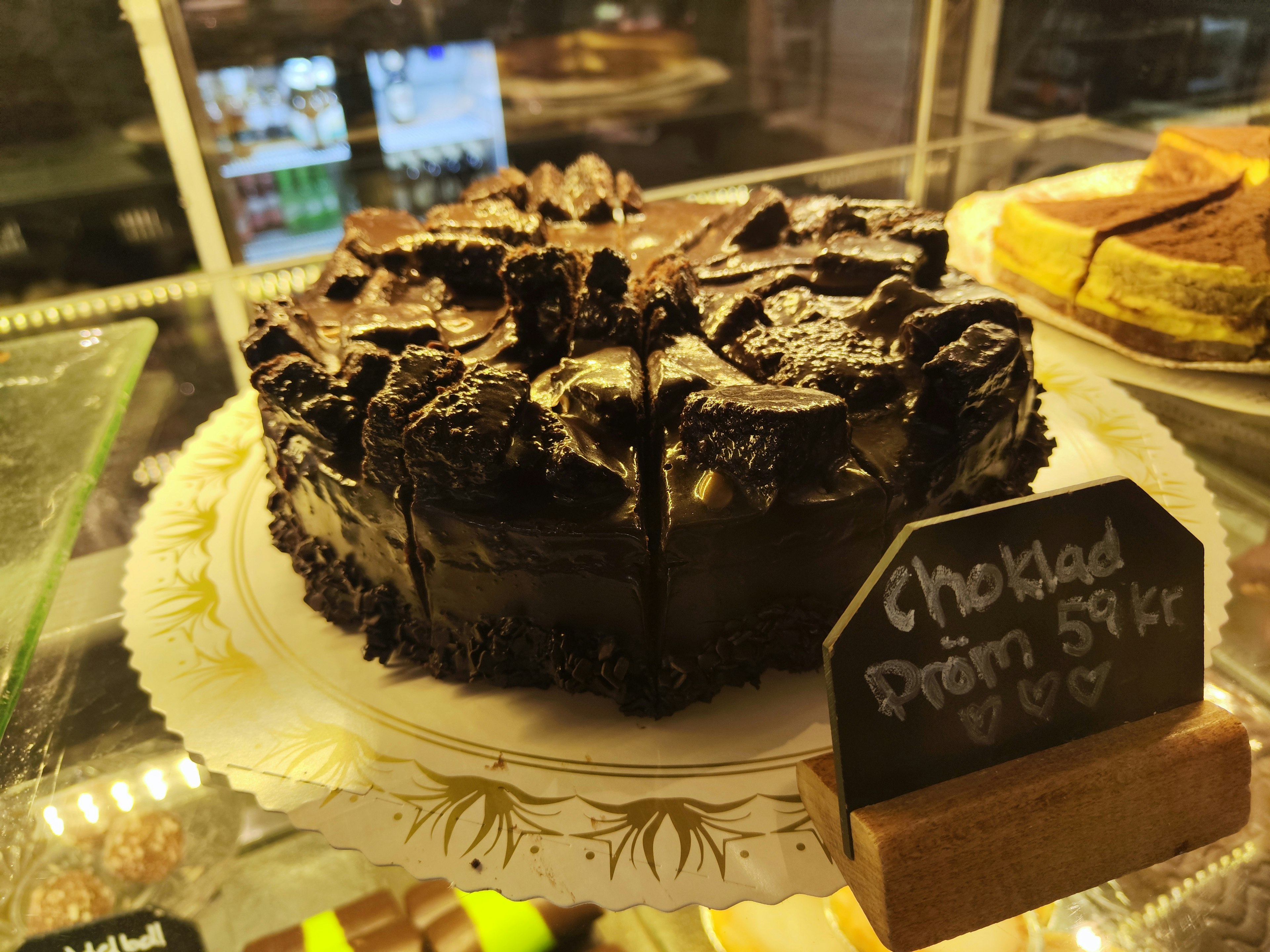 Chocolate cake topped with Oreo cookies displayed in a pastry case