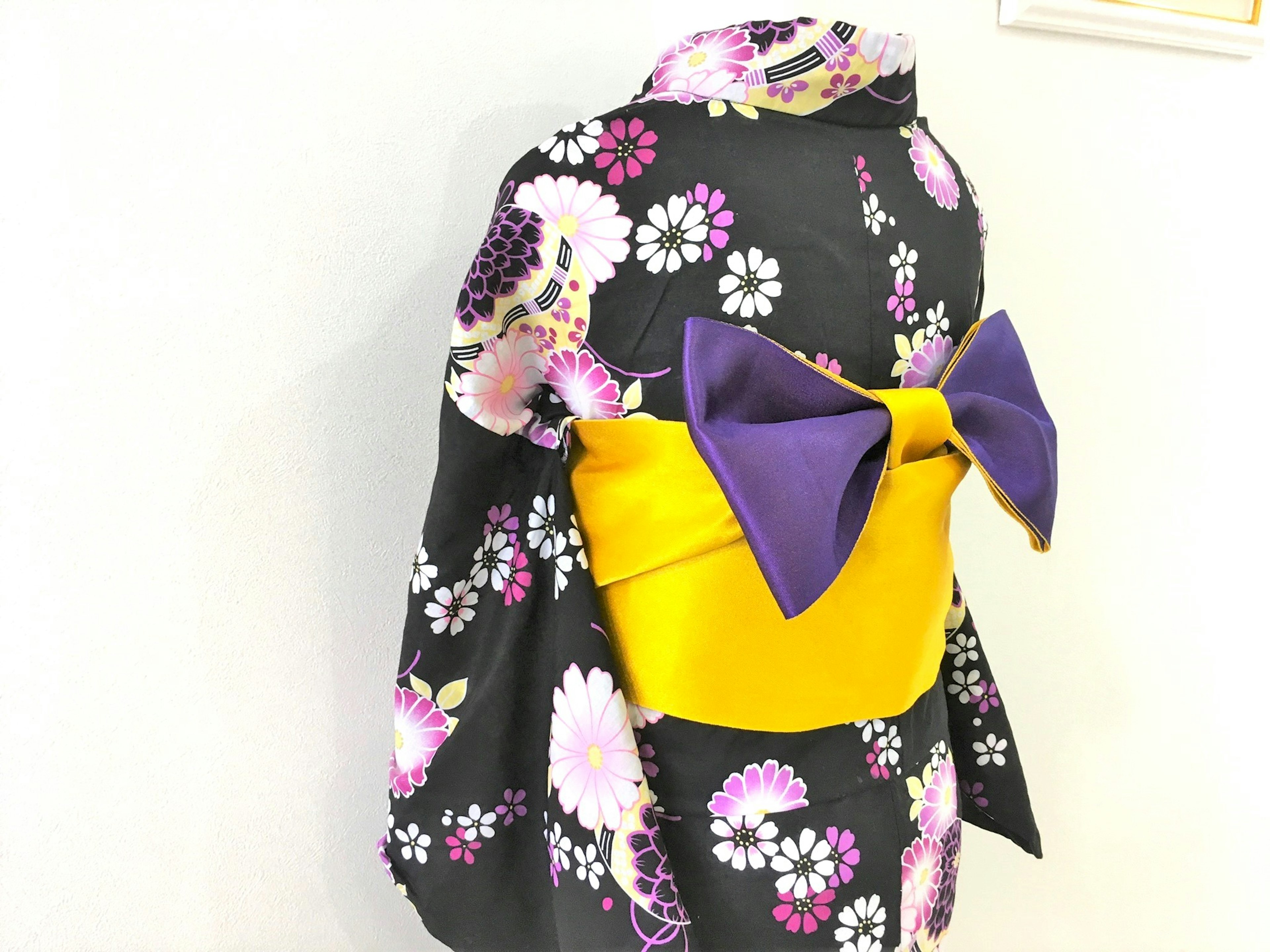 Kimono negro con patrón floral púrpura y blanco y lazo obi amarillo