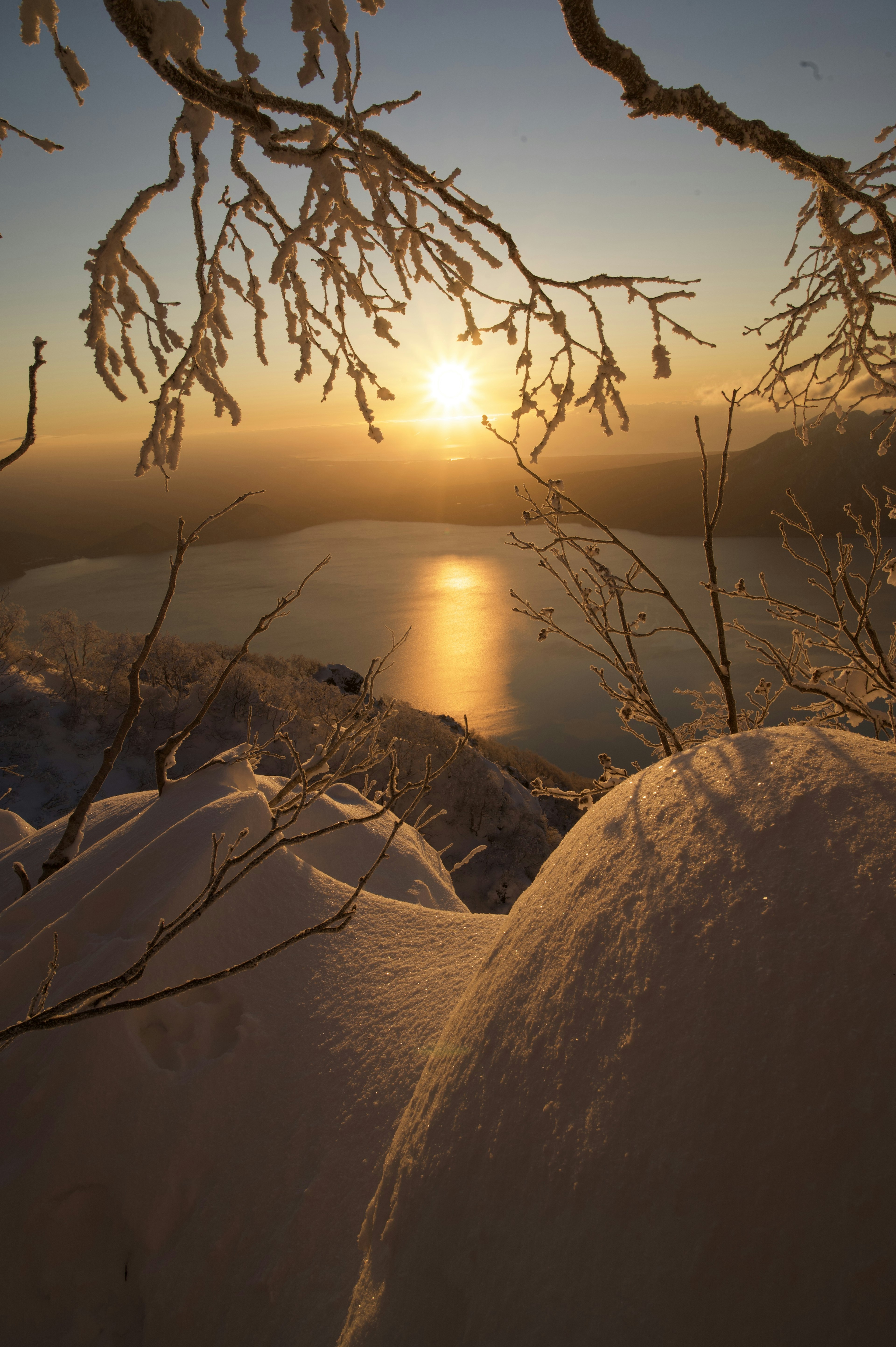 美しい夕日が雪で覆われた山々と湖に映る冬の風景