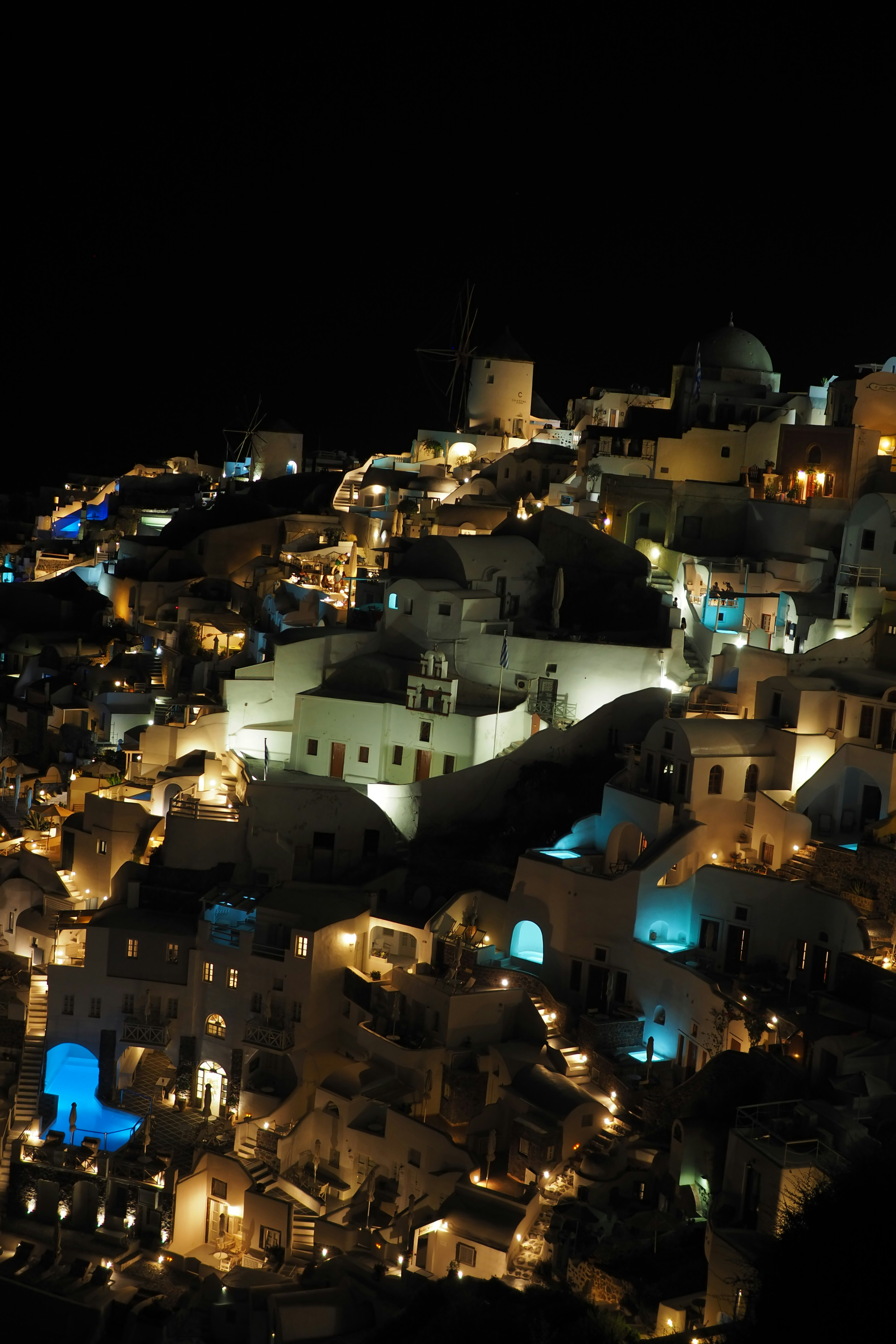 Vista notturna di Santorini con edifici bianchi illuminati e luci blu