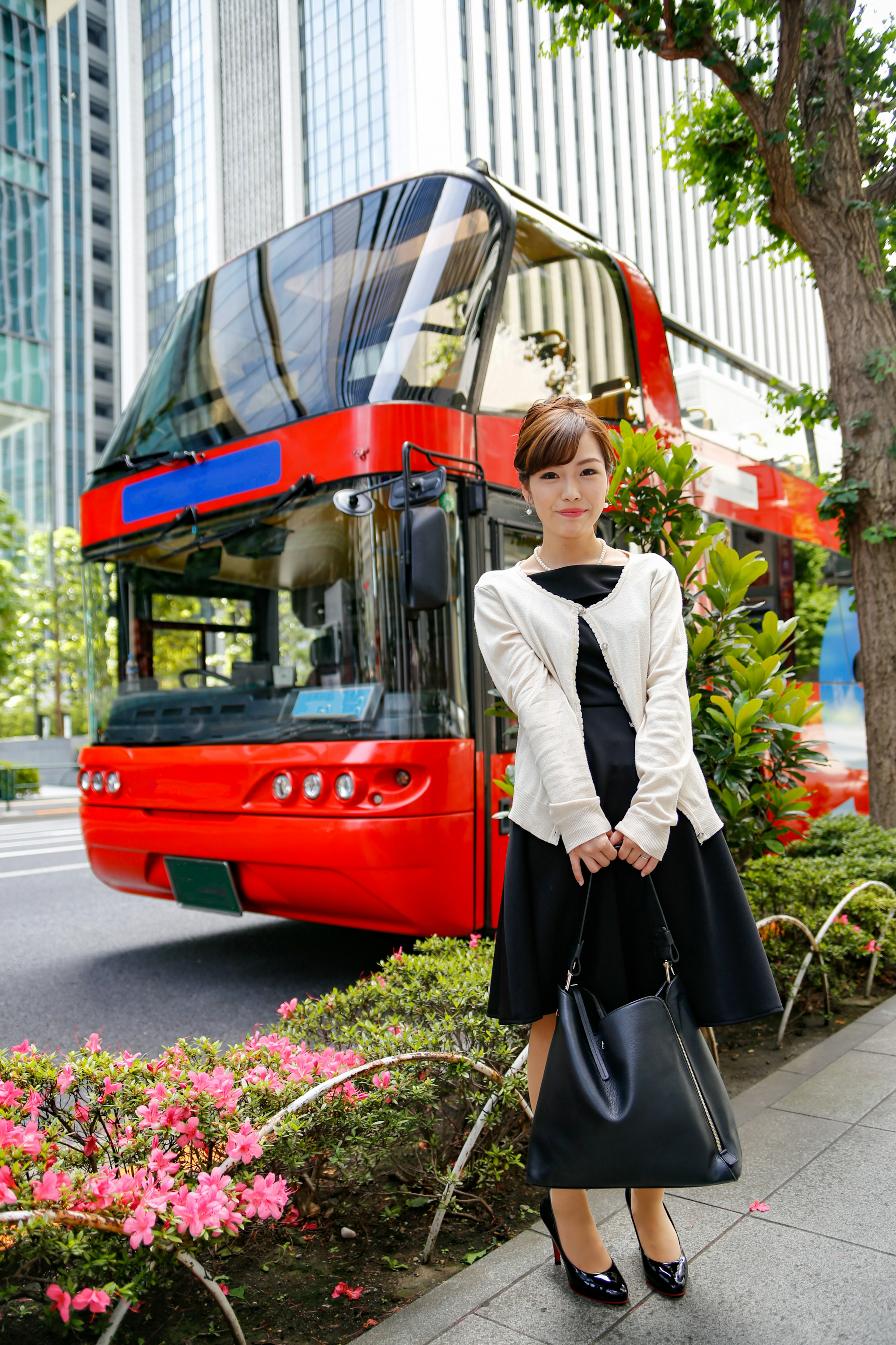 A woman standing in front of a red double-decker bus