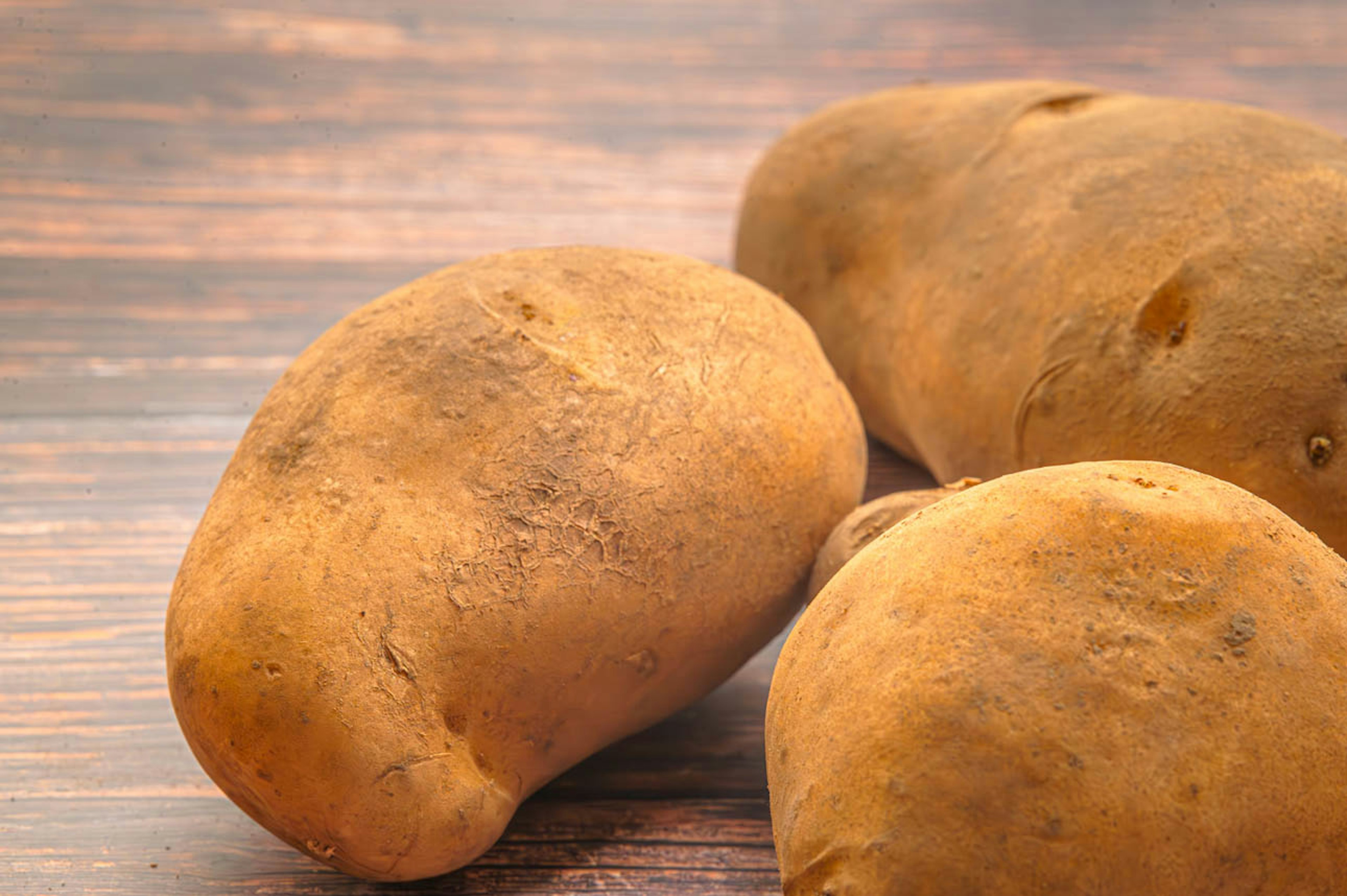 Close-up of three potatoes on a wooden table