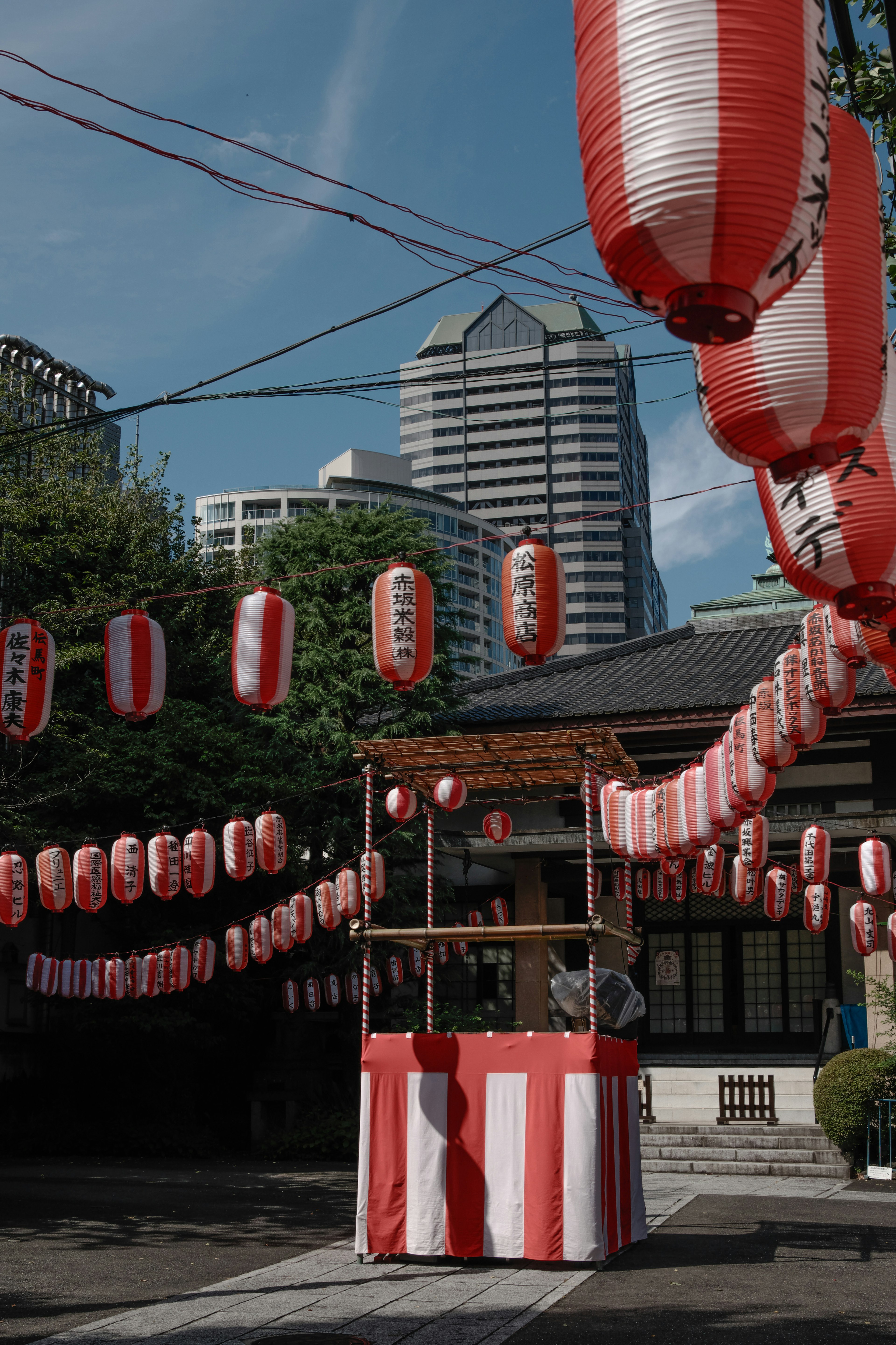 Tempat festival yang dihiasi lentera merah dan putih dengan gedung pencakar langit di latar belakang