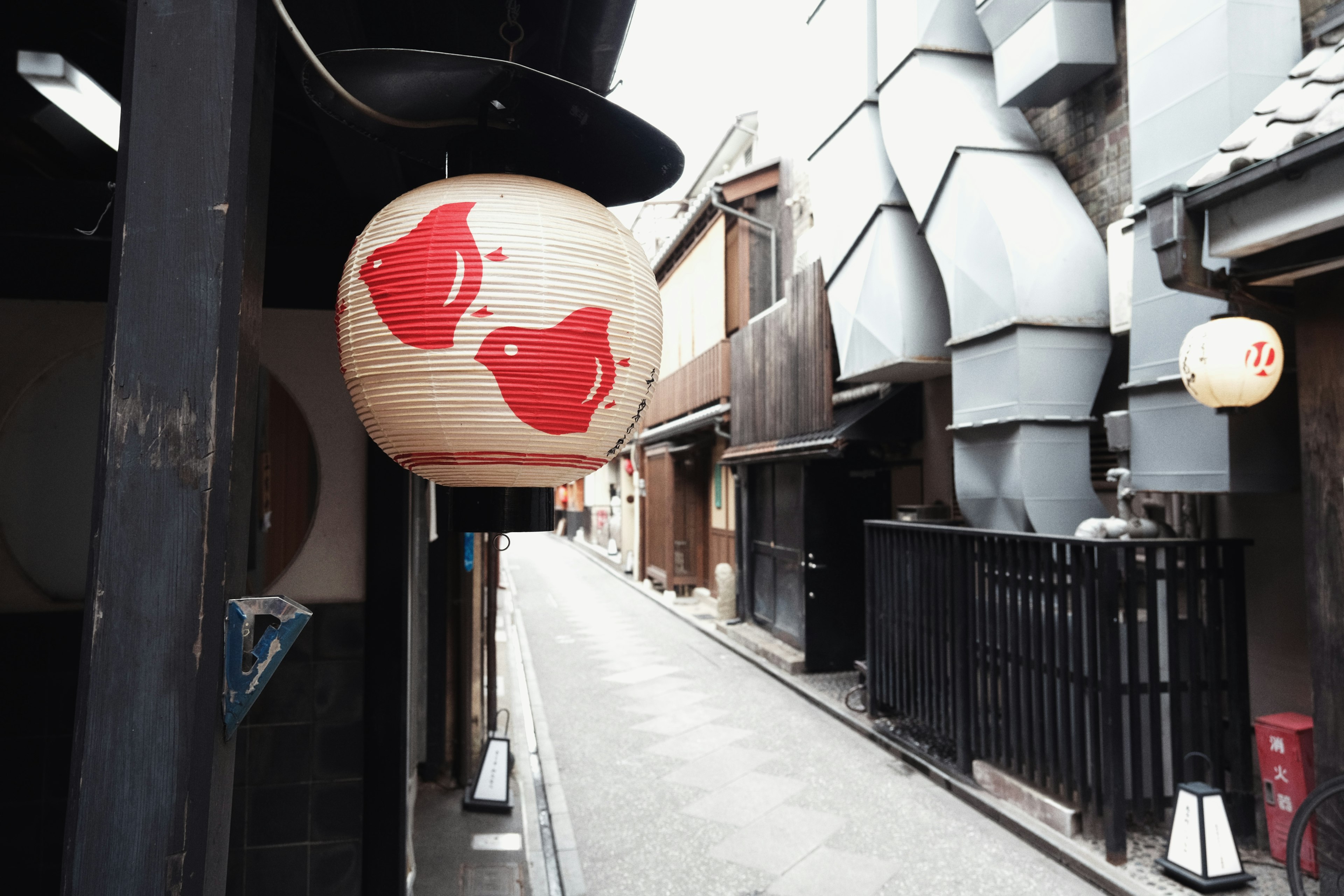 A narrow alley with a lantern featuring red goldfish hanging