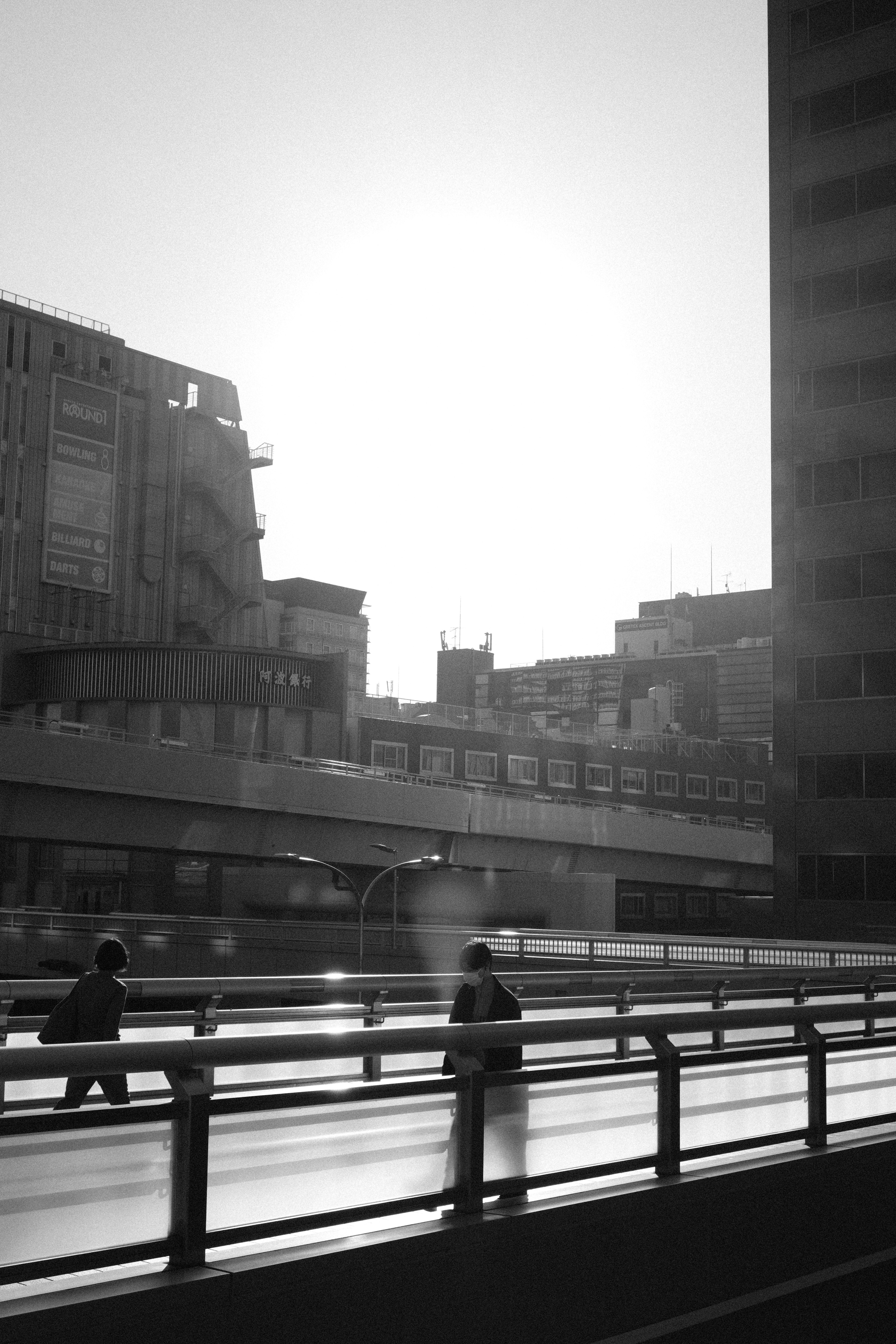 Silhouette de personnes marchant dans un paysage urbain monochrome avec un coucher de soleil en arrière-plan