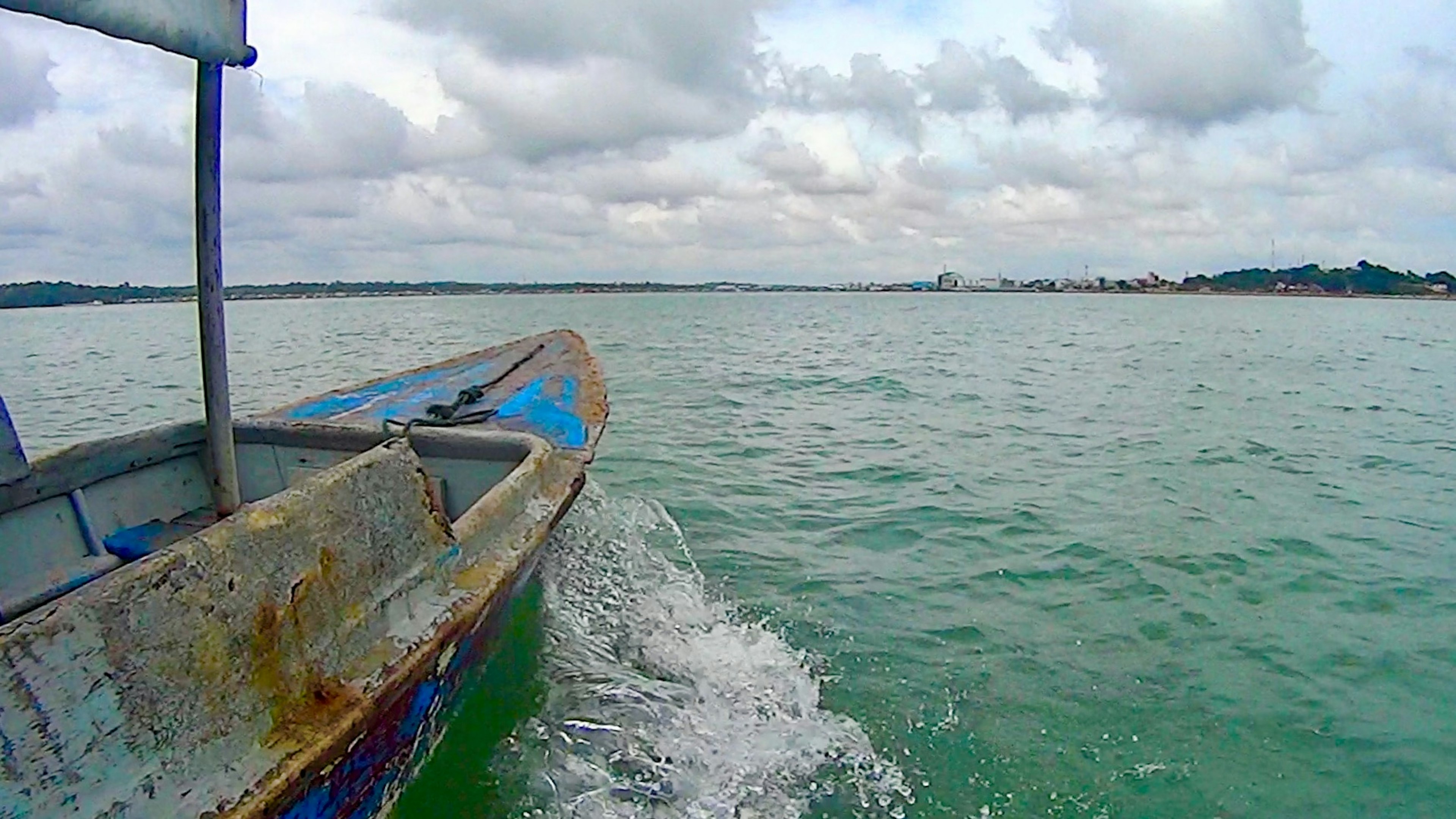 Boot bewegt sich durch Wasser mit blauen Tönen und bewölktem Himmel