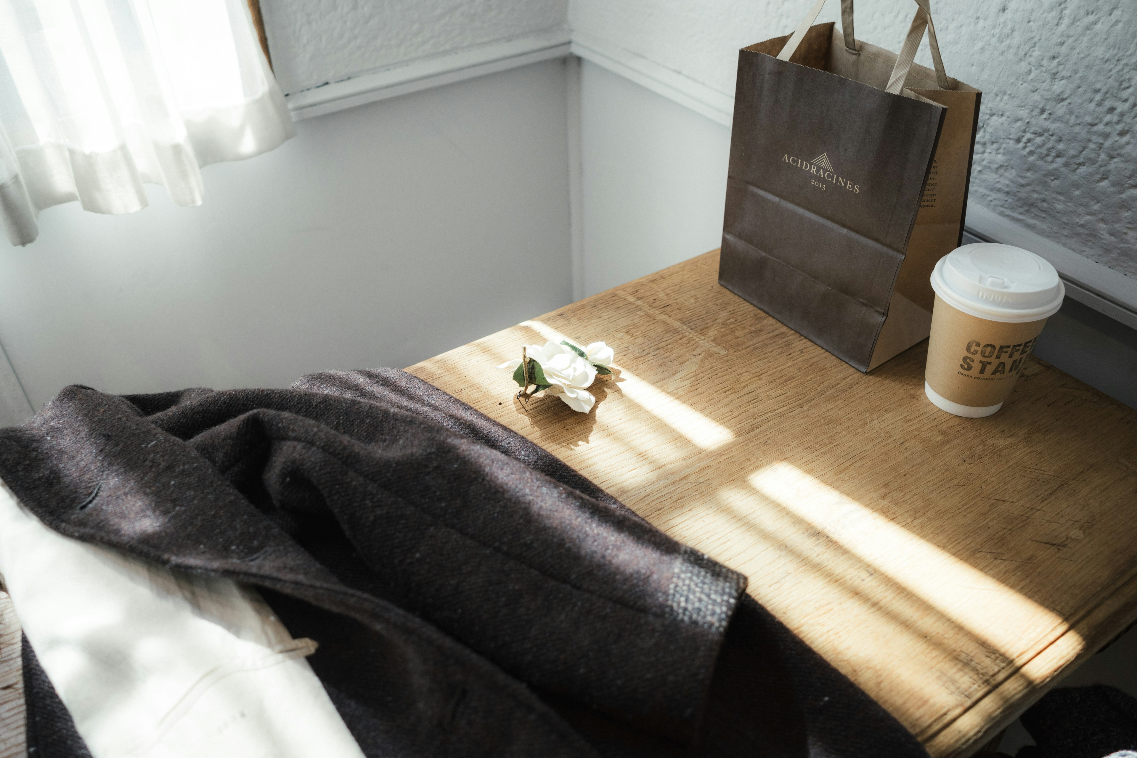 A wooden table with a coffee cup and a paper bag