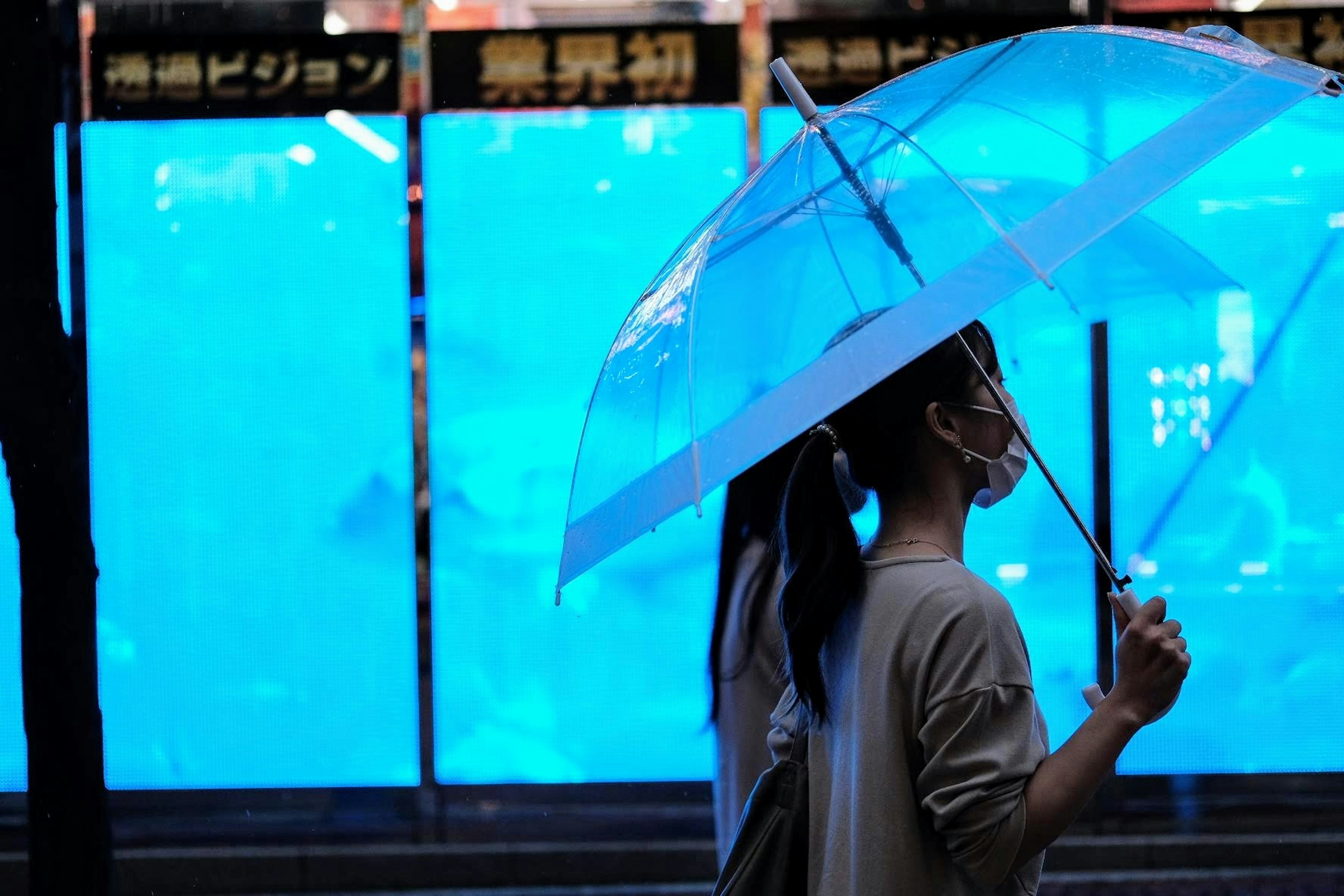 Frau, die nachts mit einem blauen Regenschirm geht