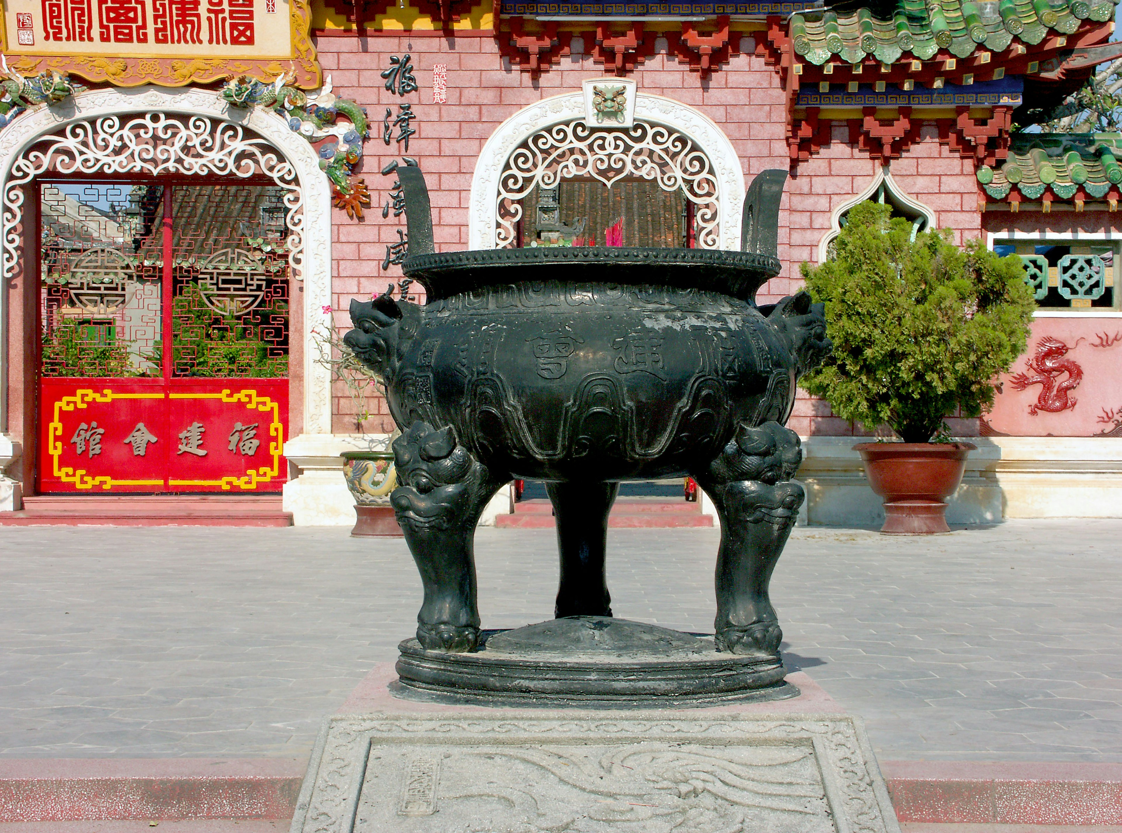 Black incense burner in front of a temple with ornate Chinese architecture