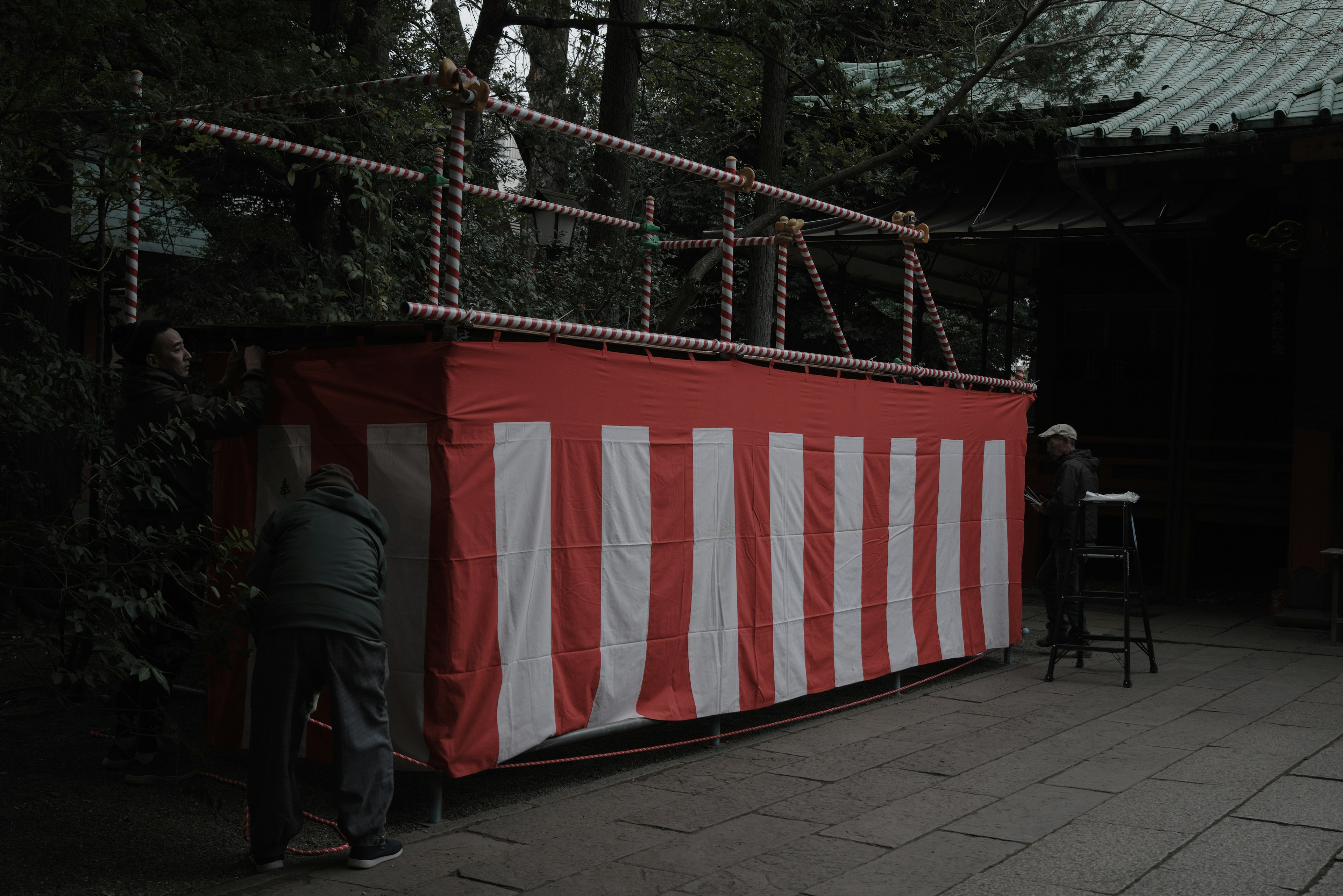 Scene of people working on a red and white striped tent being set up