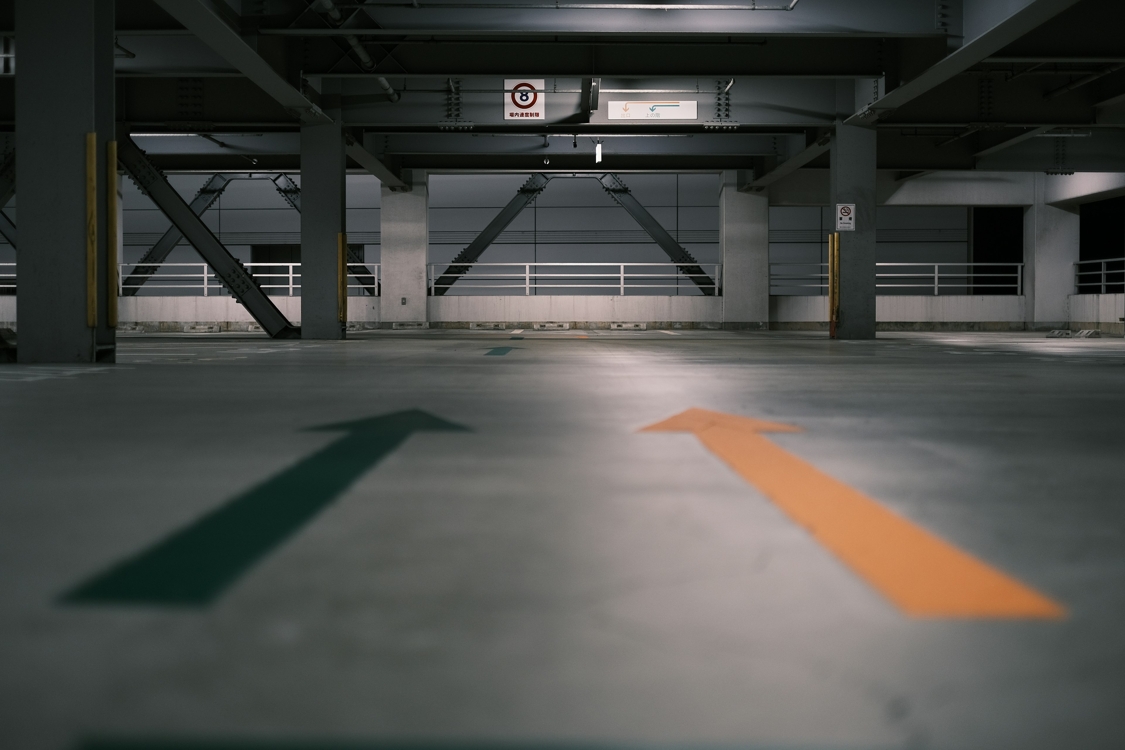 Green and orange arrows painted on the floor of a parking garage