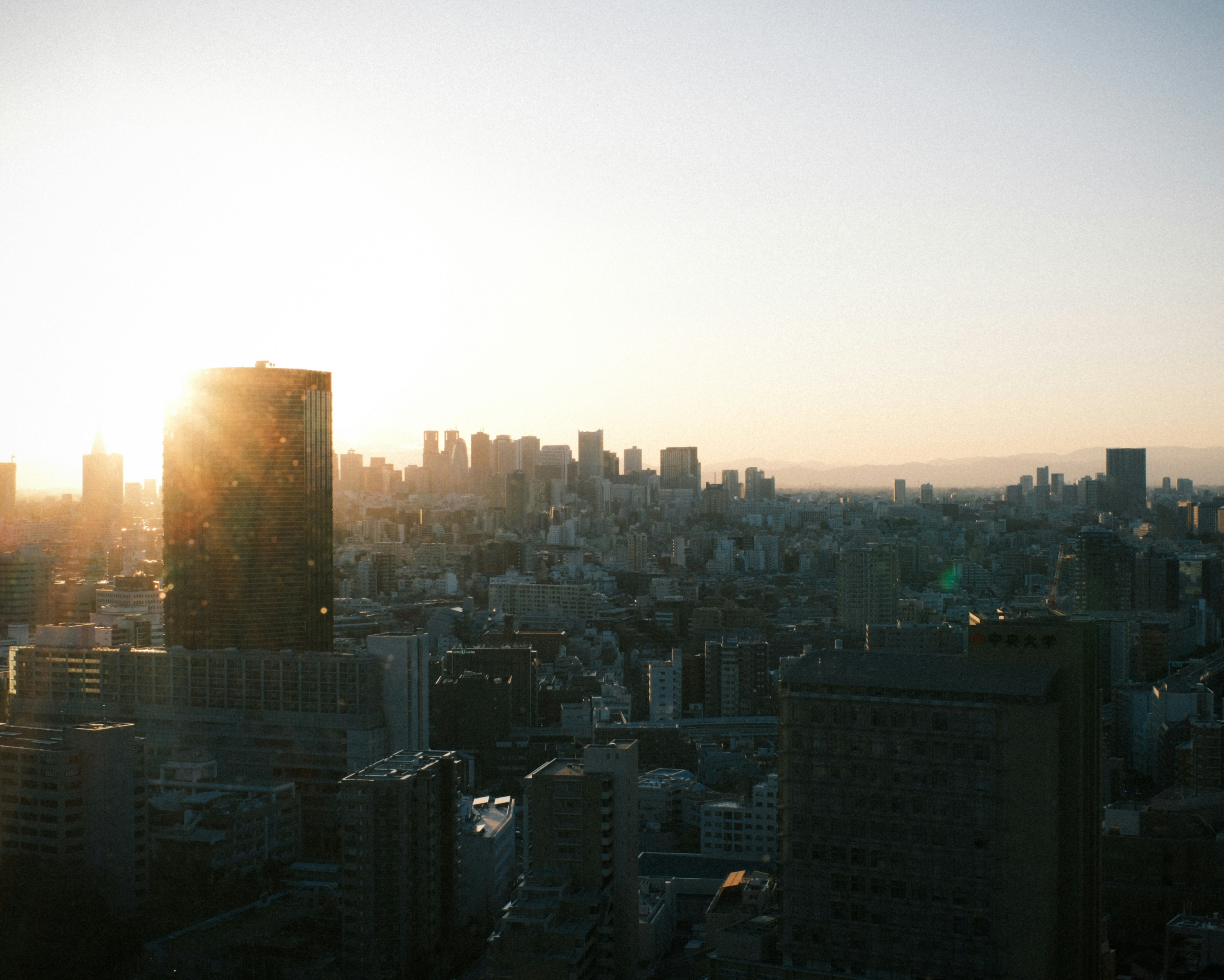 Cảnh thành phố Tokyo vào lúc hoàng hôn với các tòa nhà chọc trời và ánh sáng vàng