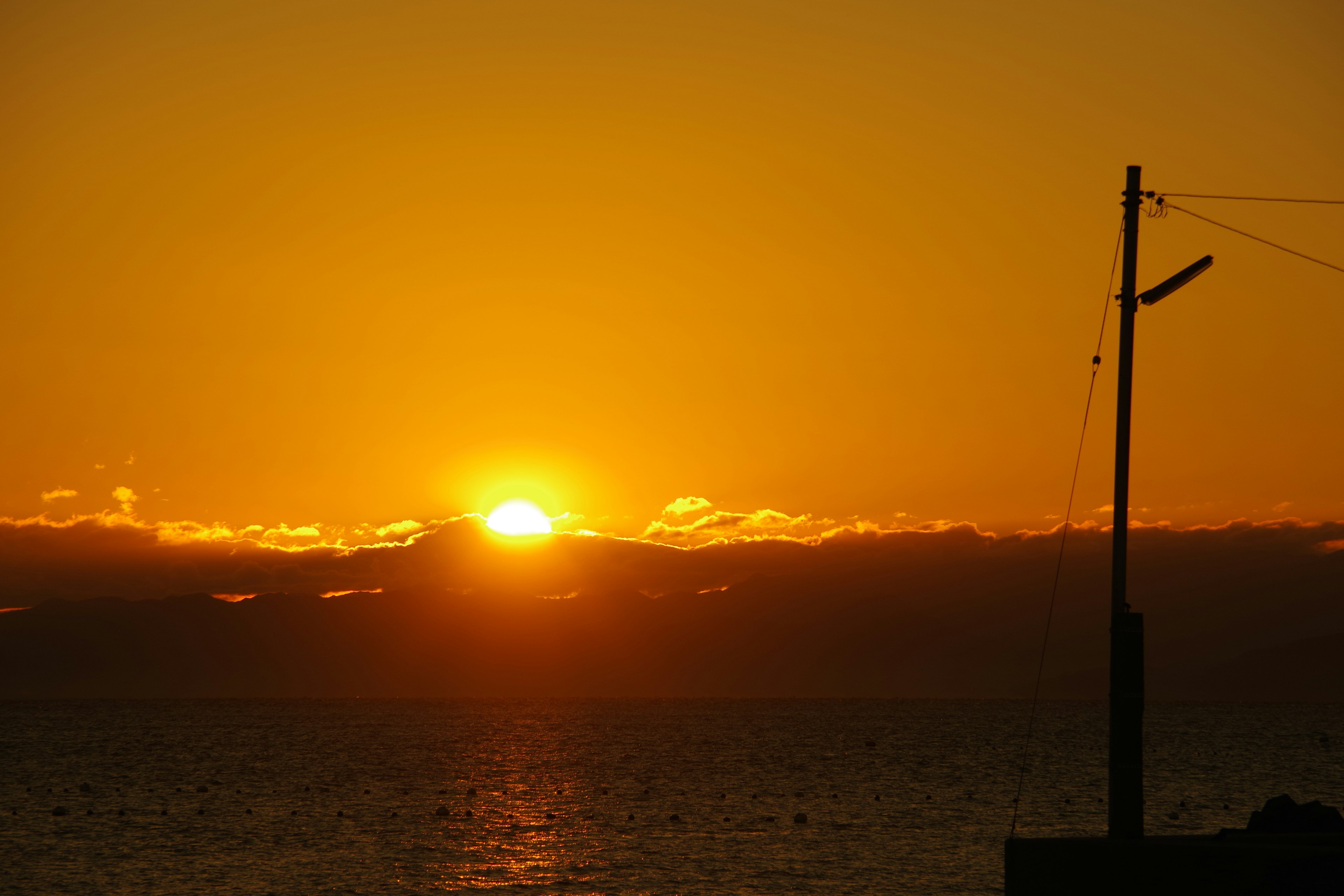 Schöner Sonnenuntergang über dem Ozean mit einem silhouettierten Strommast