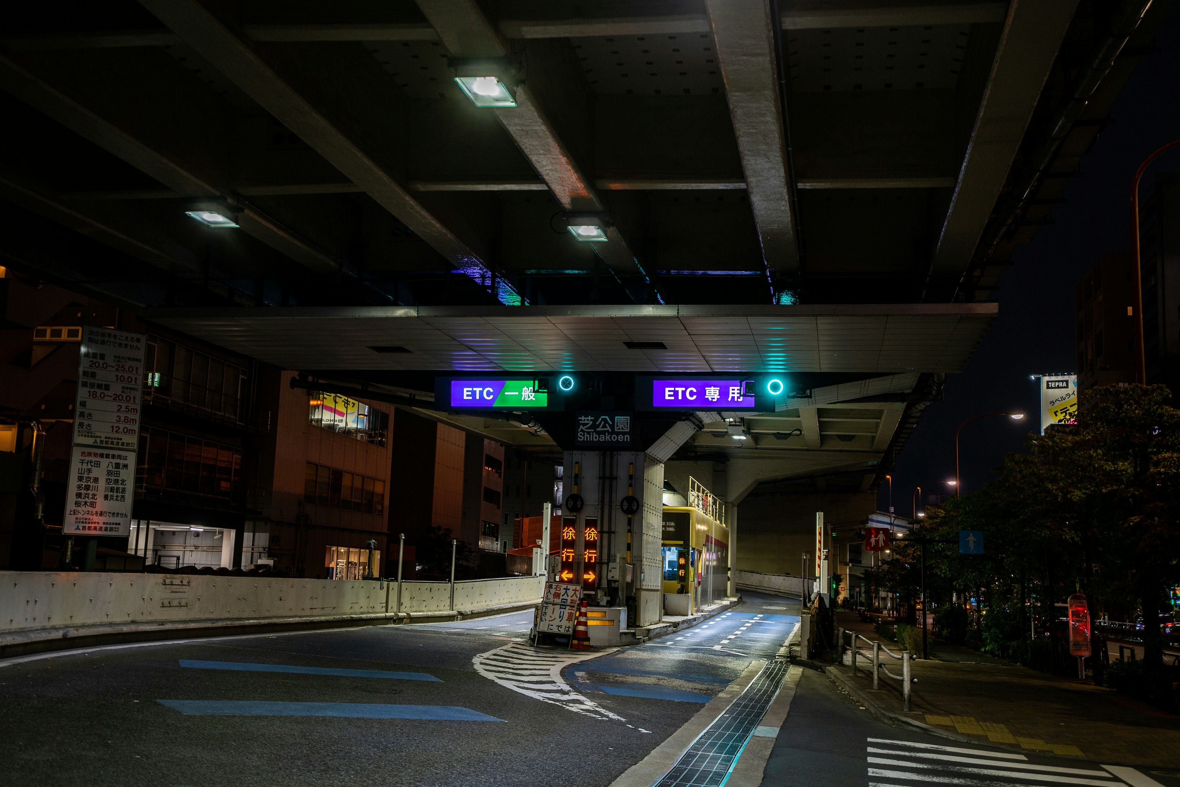 Traffic signals and directional signs under an elevated road at night in a city