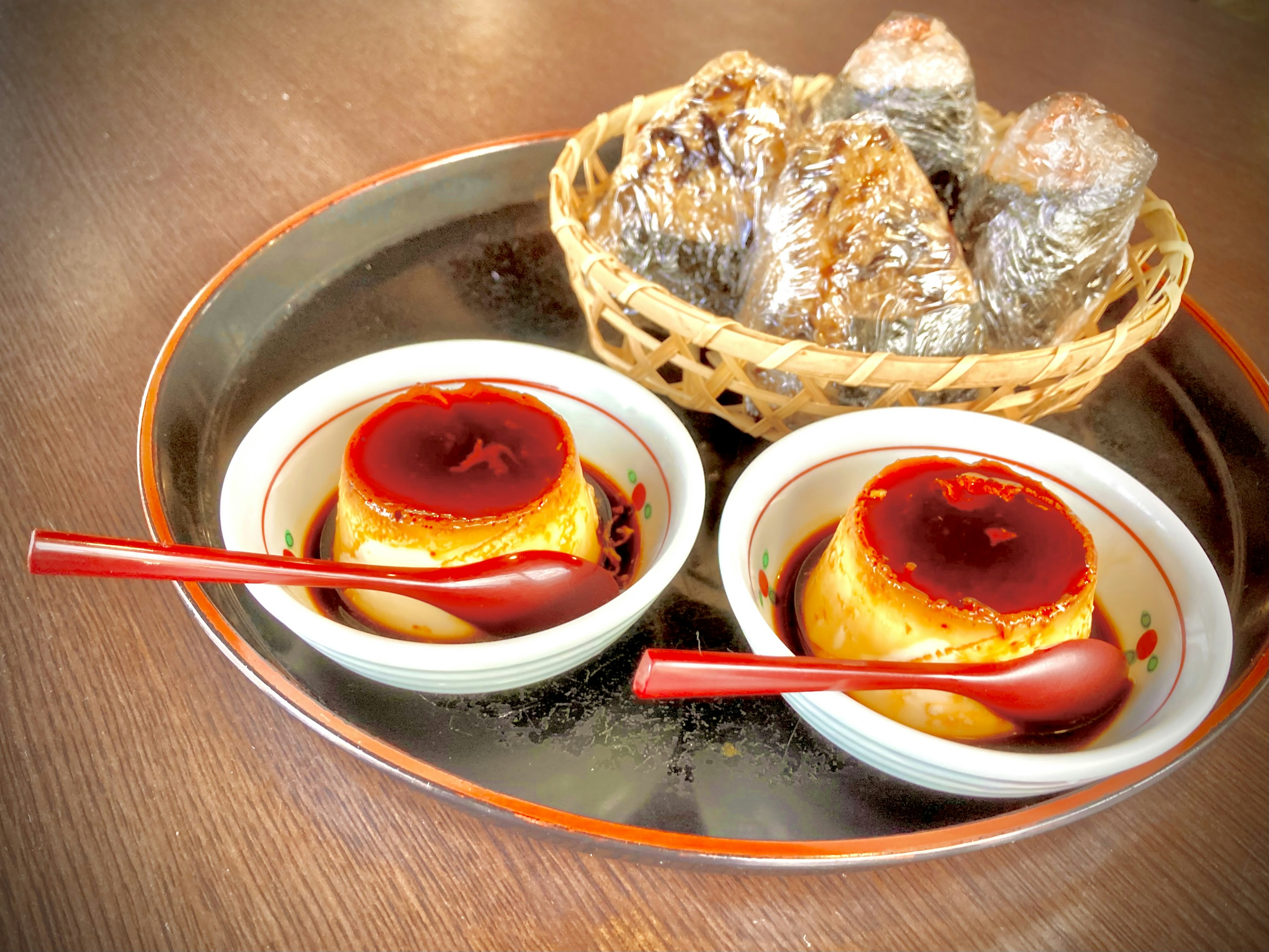 Zwei Puddings mit Karamellsauce und Reisbällchen in Bambusblättern