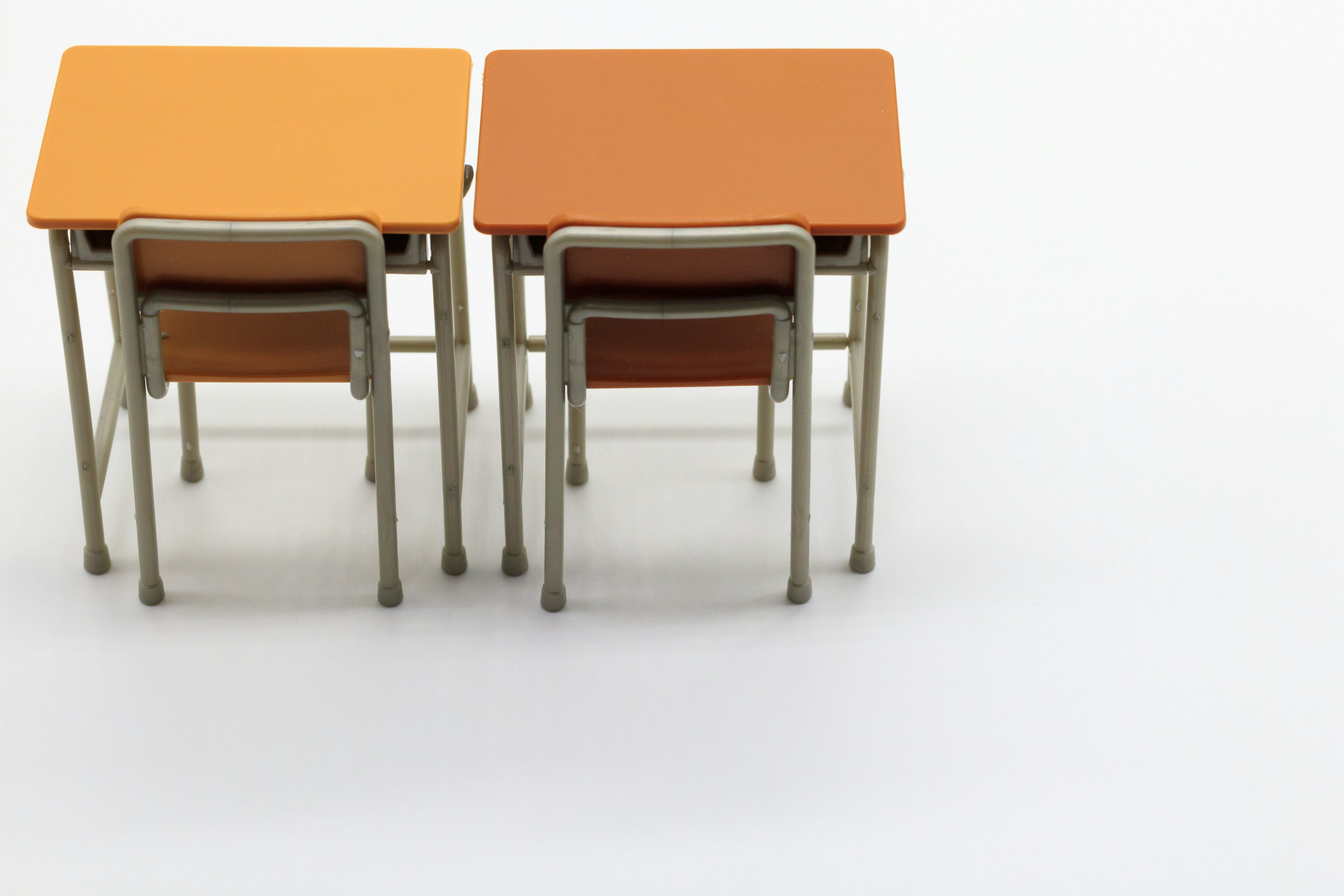 Two orange desks with chairs arranged in a minimalist classroom setting