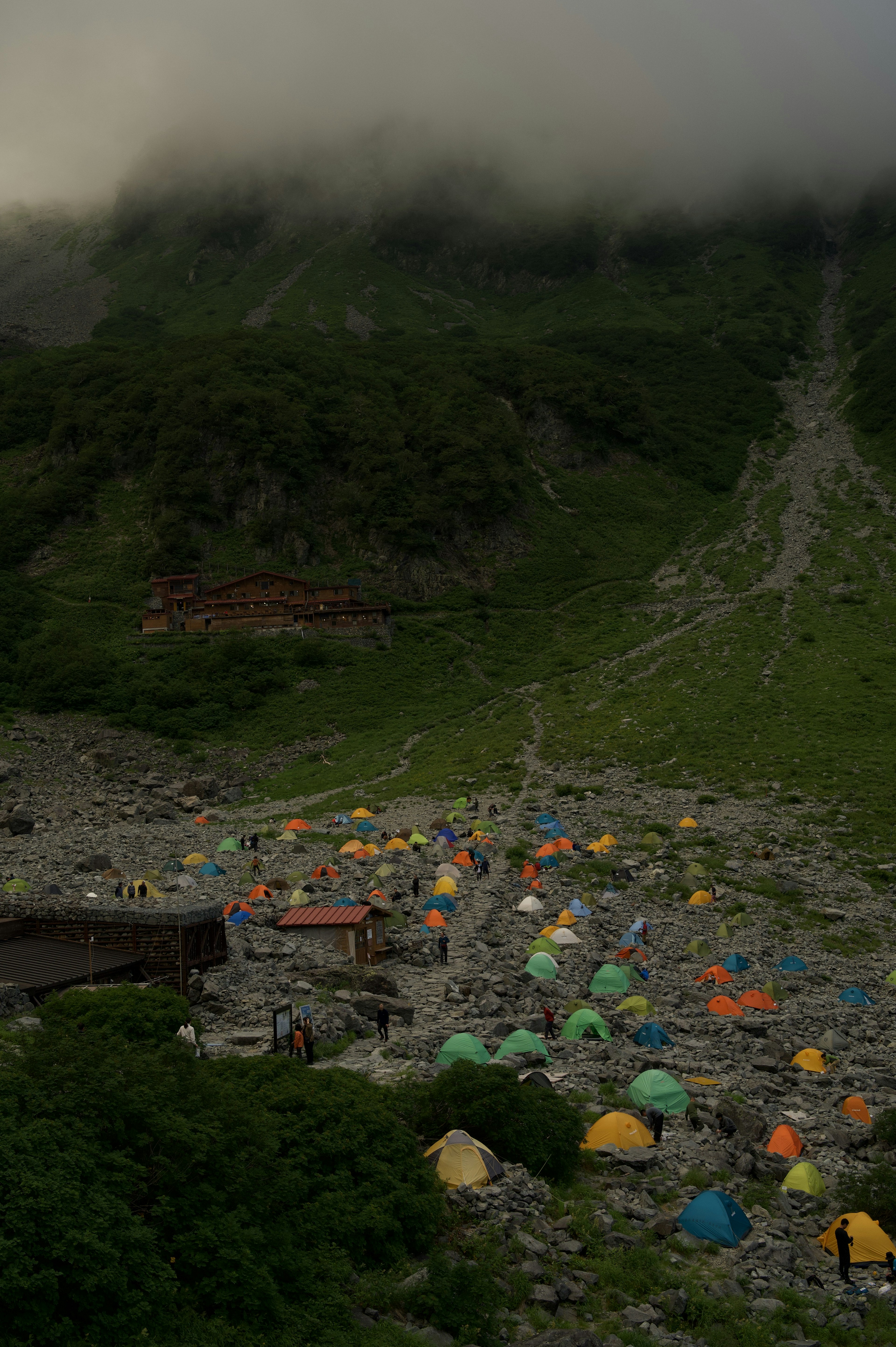 被雾气笼罩的山中露营地 彩色帐篷散布在风景中