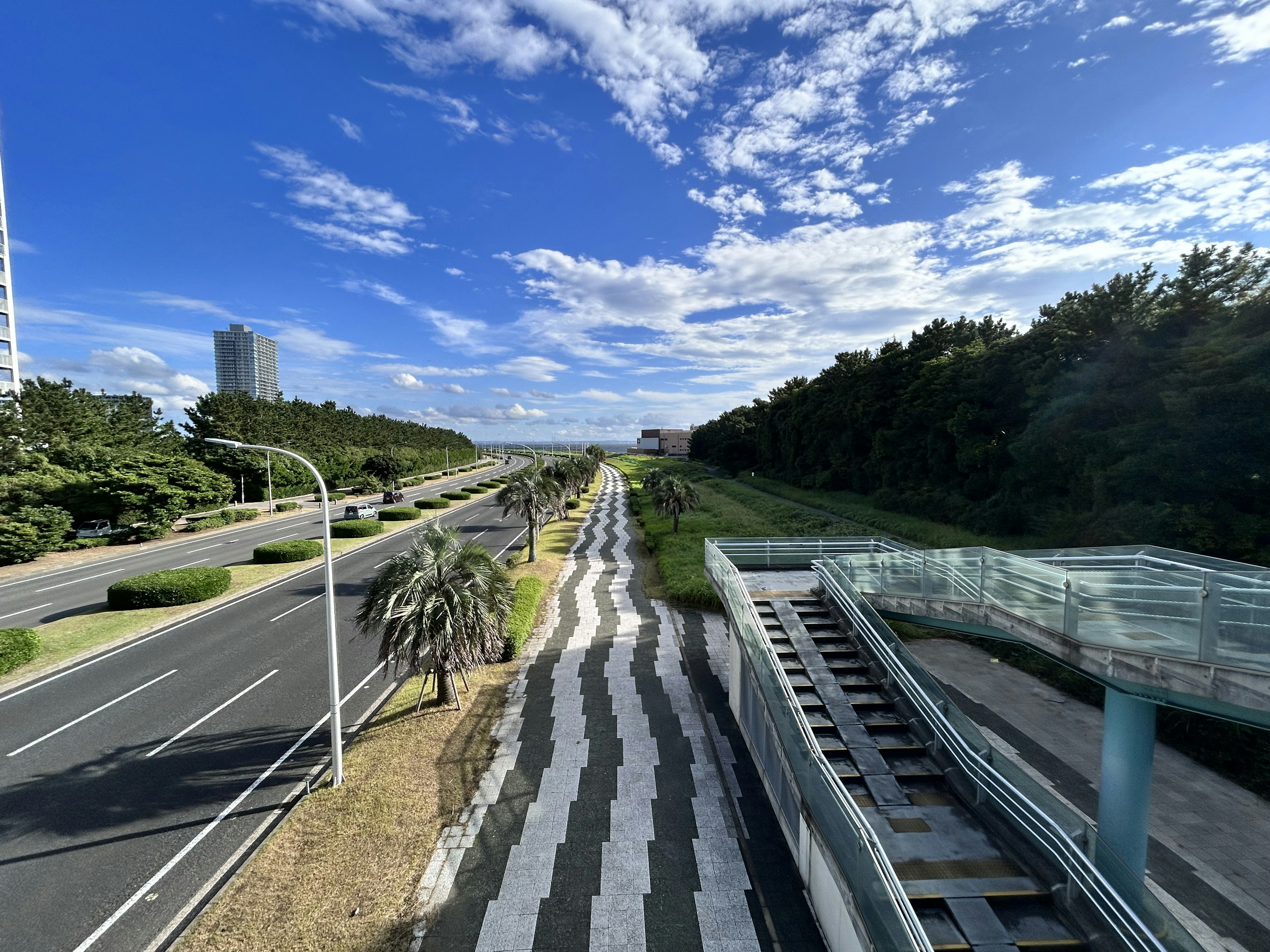 A scenic view of a road with blue sky and greenery