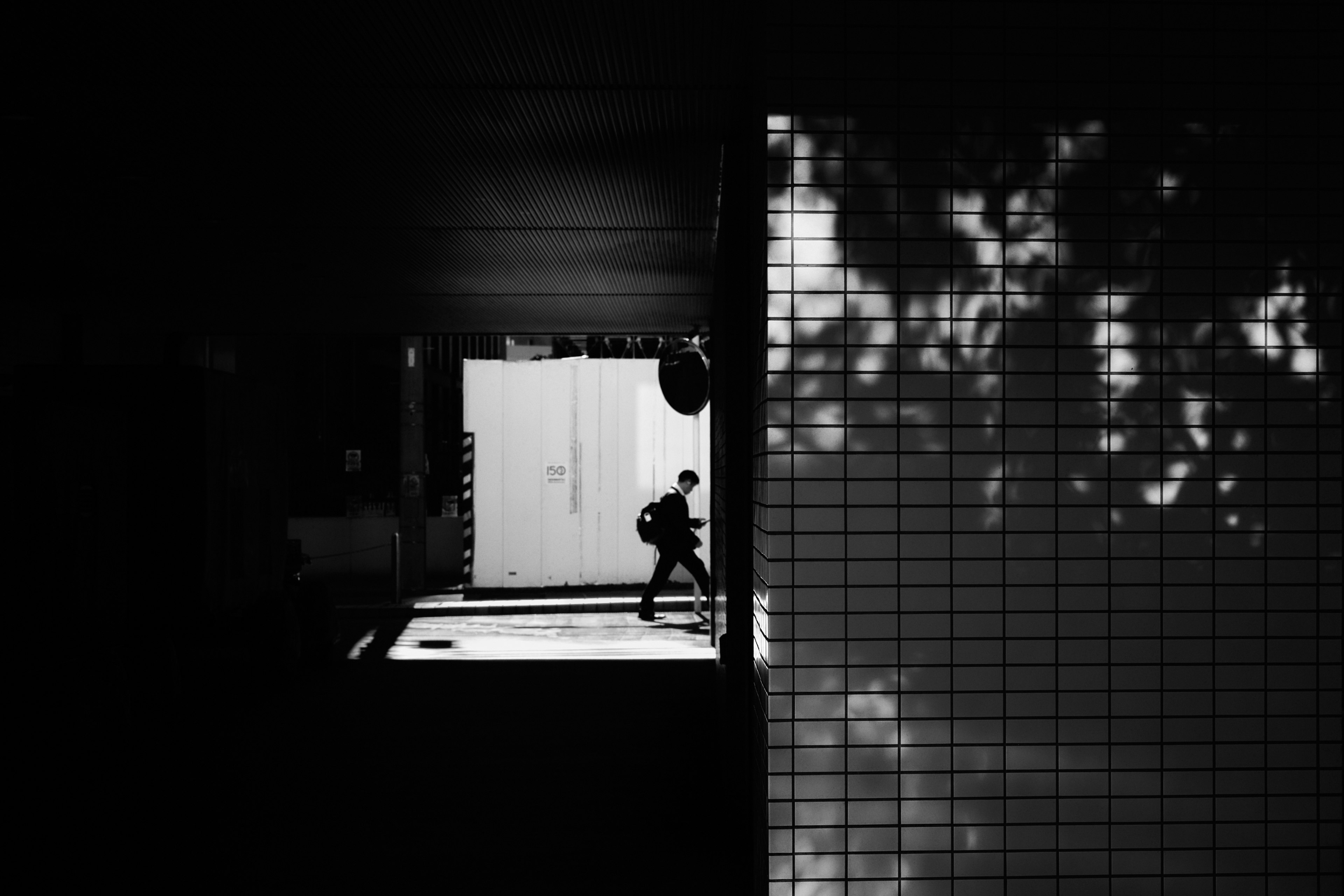 Silhouette of a person walking through a doorway in high contrast black and white