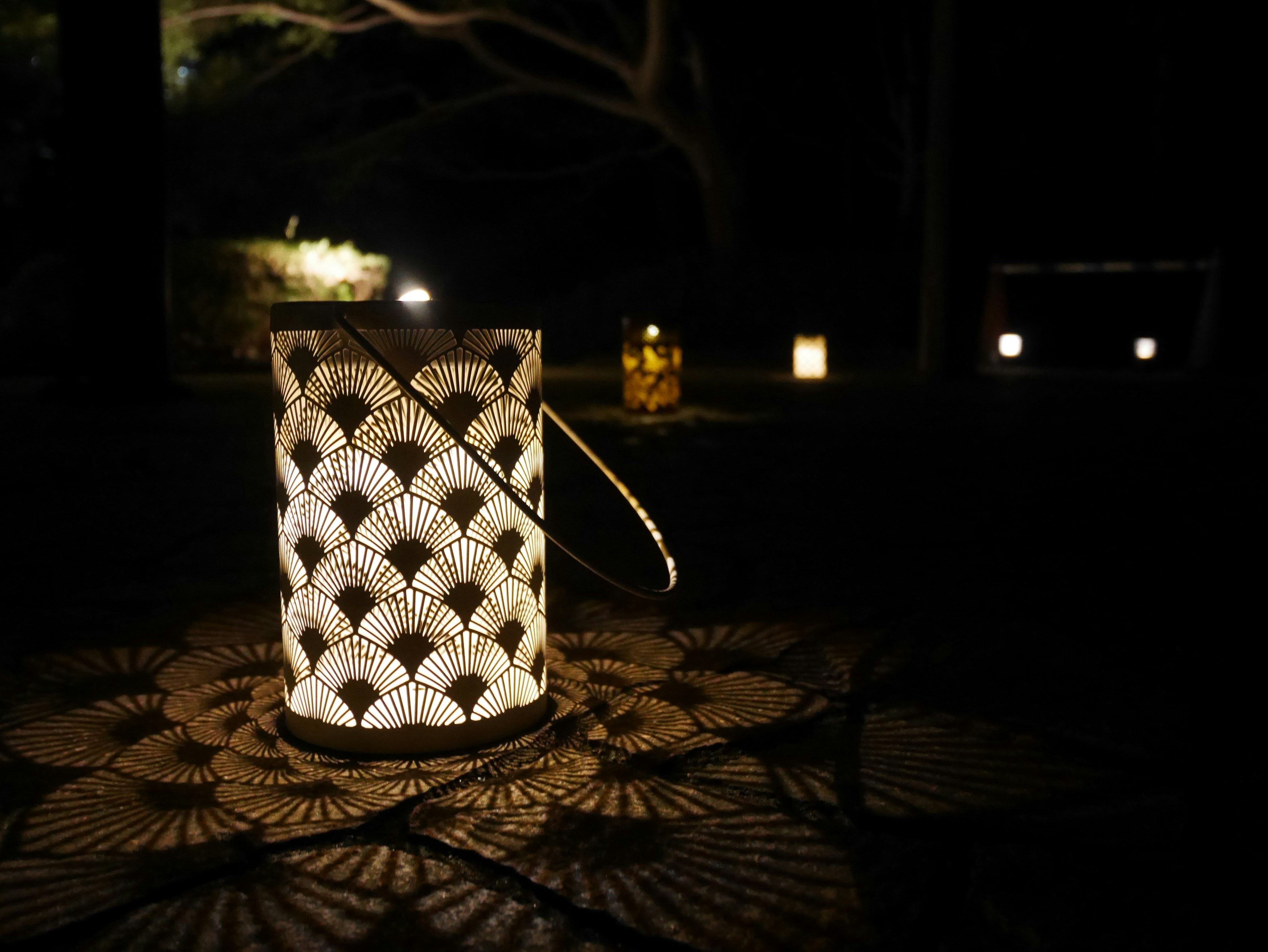 Lanterne décorative placée dans un jardin sombre avec une table à motifs