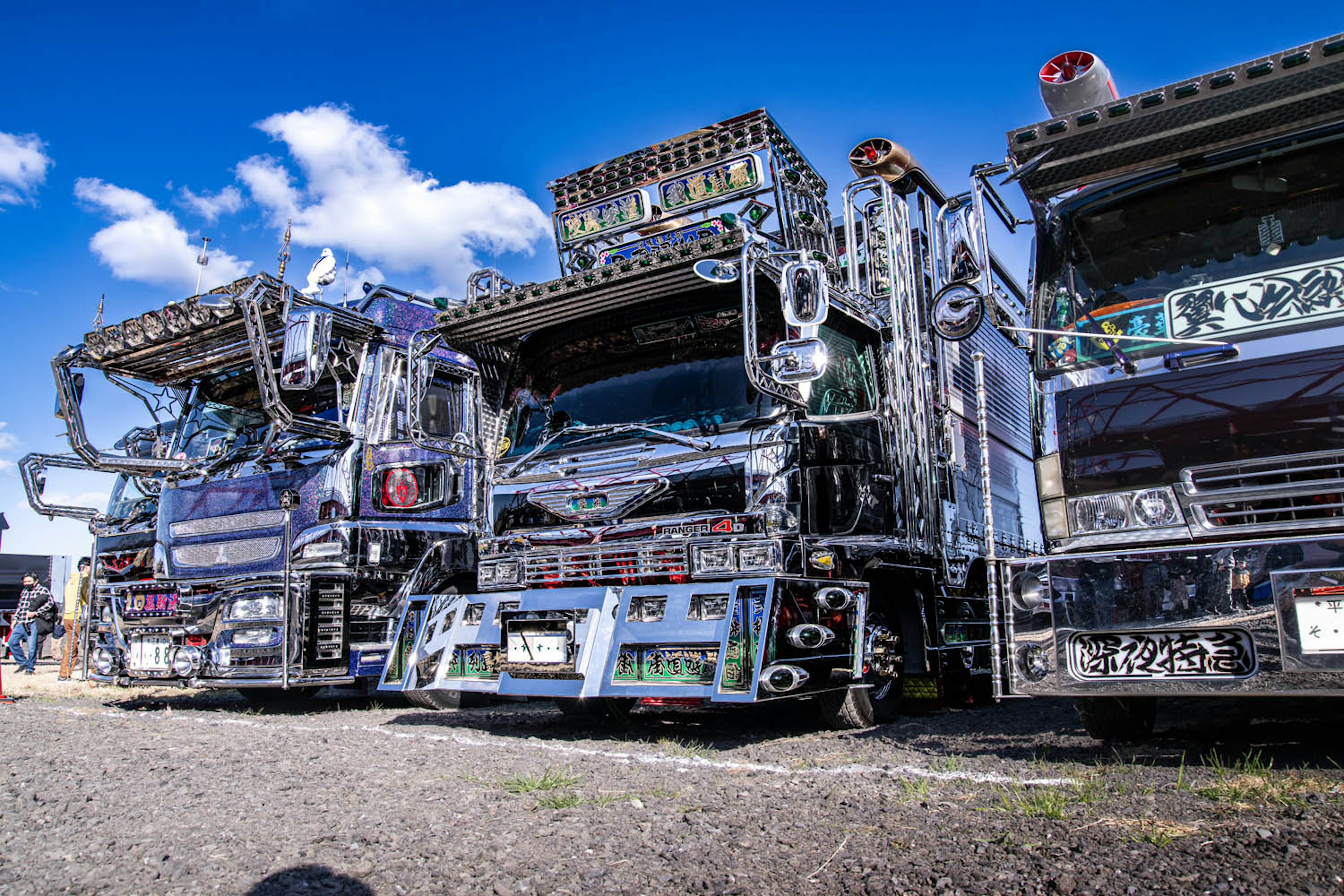 Row of custom trucks showcasing unique designs under a blue sky