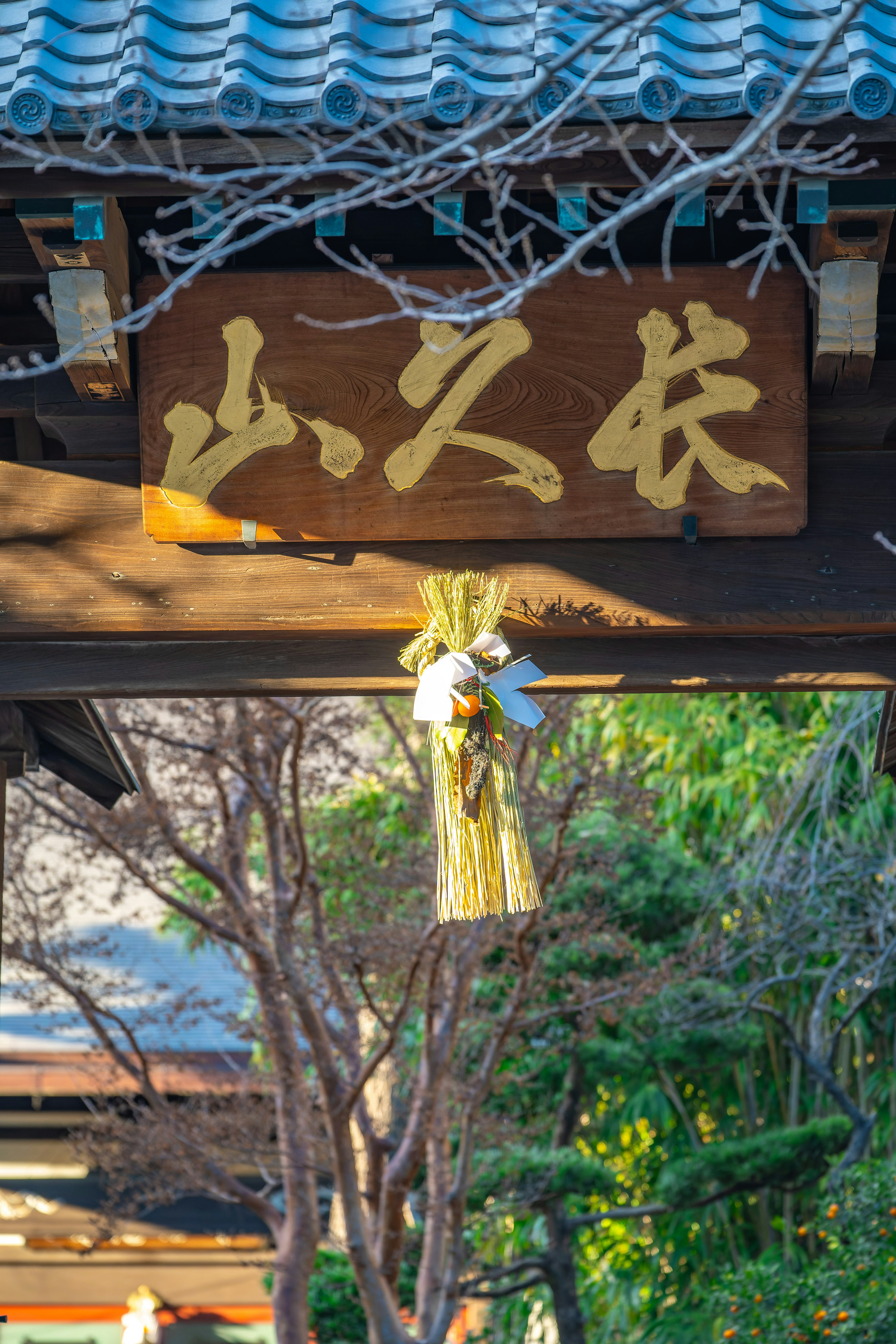 Holzschild an einem Tor mit goldener Schrift und dekorativer Quaste