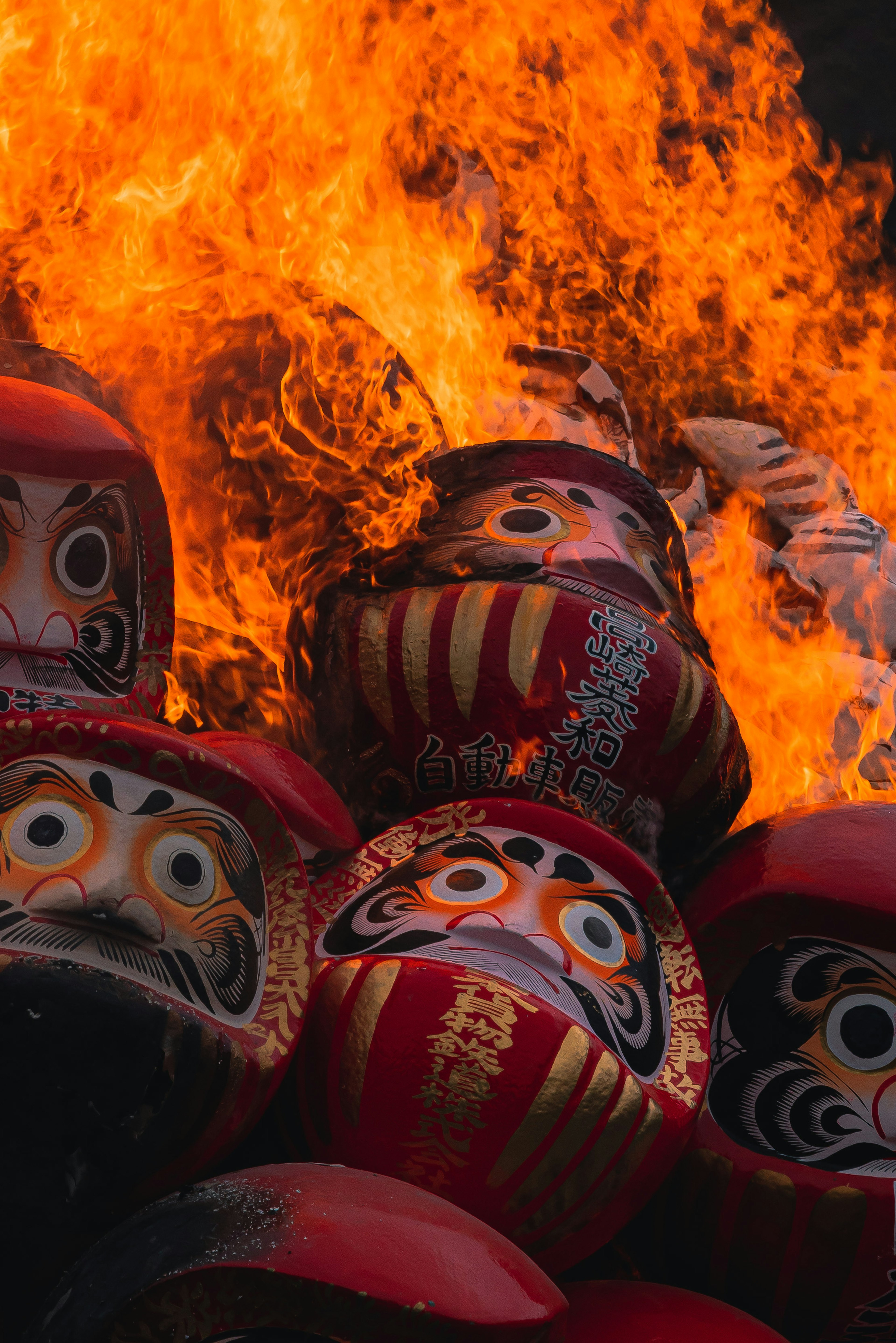 Daruma dolls stacked amid flames