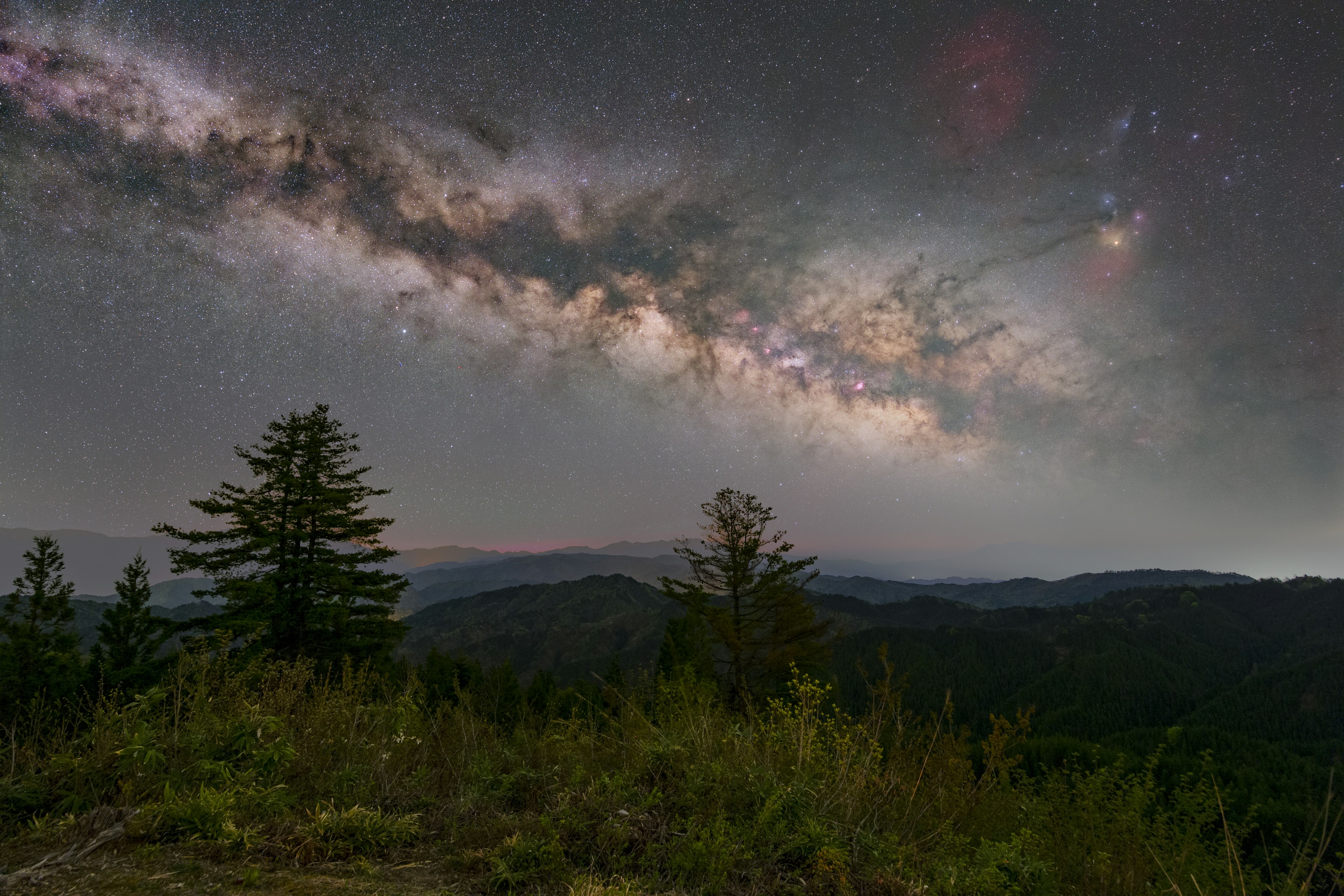 星空の下に広がる山々と木々のシルエット